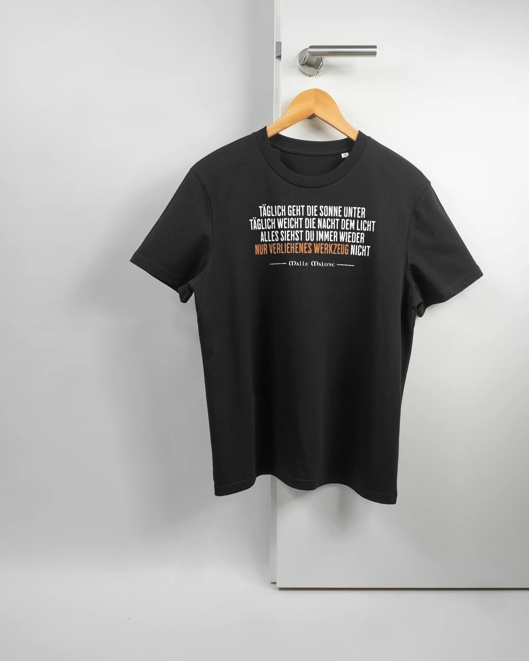 Vorderseite des Organic Unisex T-Shirt Casual von Maondo mit dem Design Wegzeug in der Farbe Black und in der Größe S auf einem Bügel an der Türklinke aufgehängt
