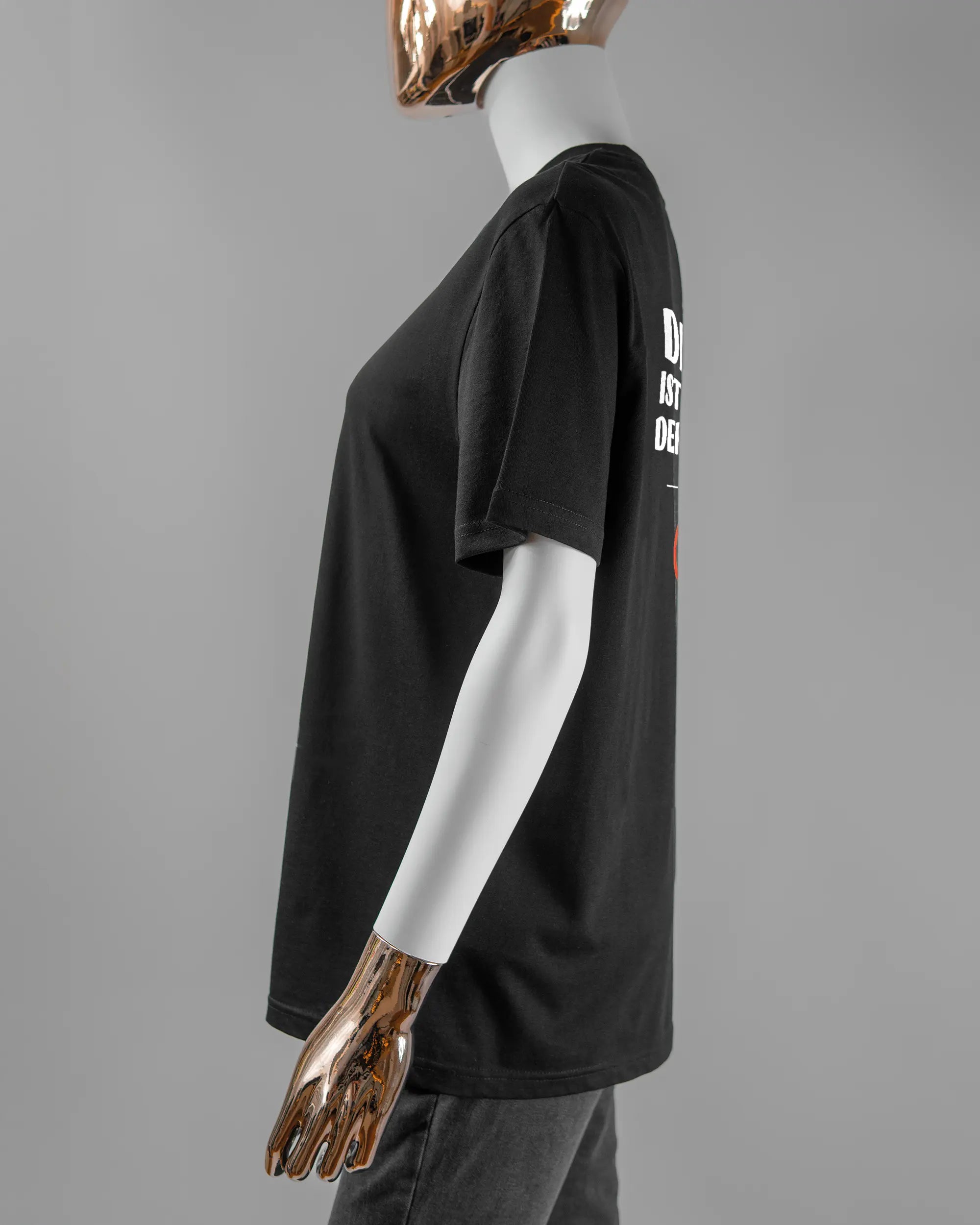 Seitenansicht des Organic Unisex T-Shirt Casual von Maondo mit dem Design Keine Eile hinten in der Farbe Black und in der Größe S getragen von einer femininen Puppe