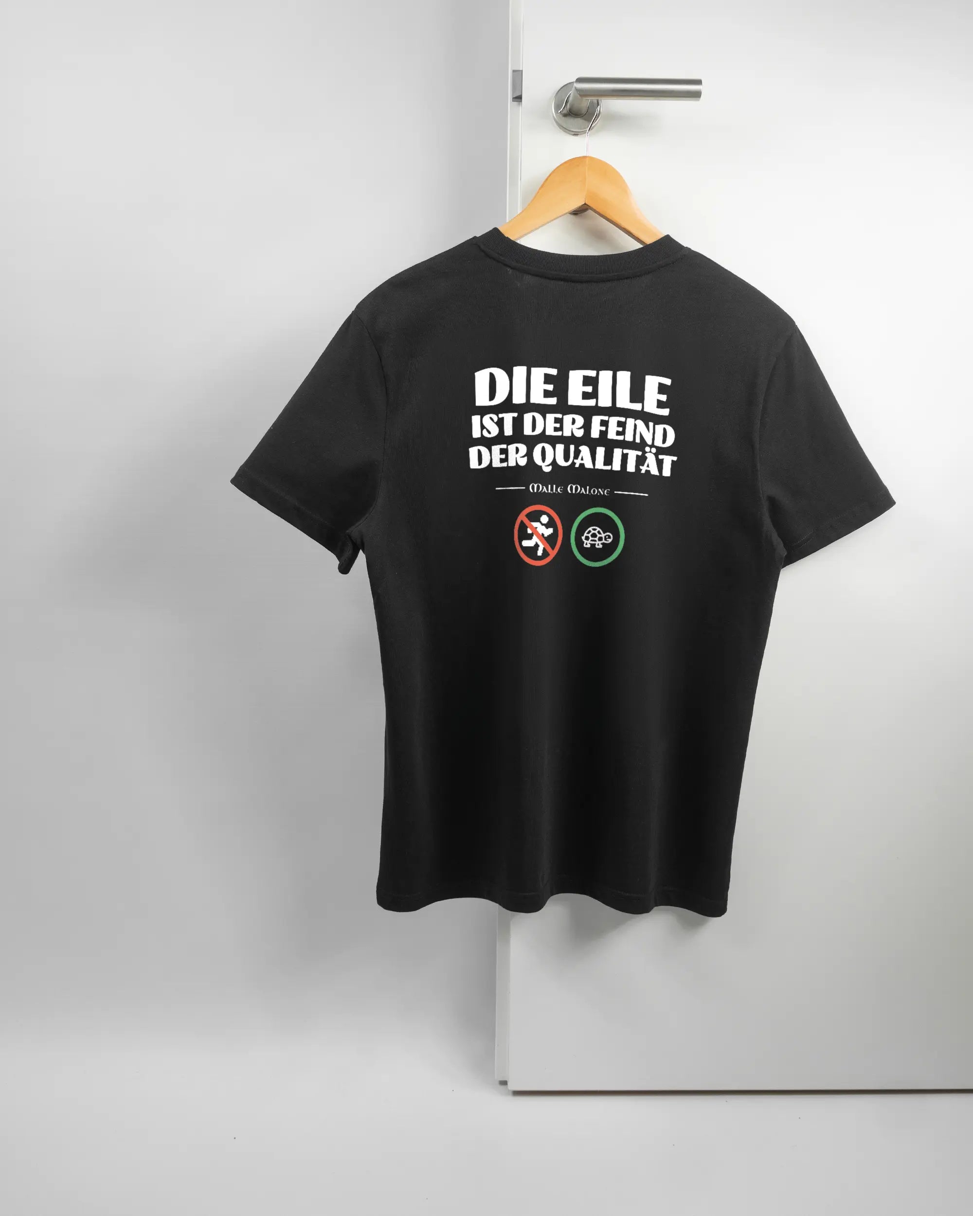 Rückseite des Organic Unisex T-Shirt Casual von Maondo mit dem Design Keine Eile in der Farbe Black und in der Größe S auf einem Bügel an der Türklinke aufgehängt