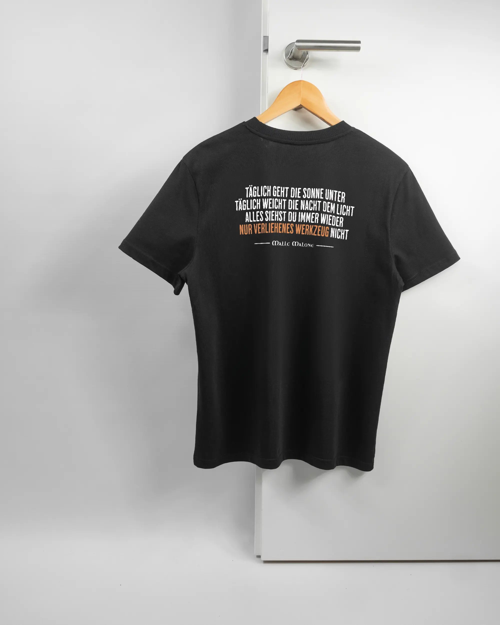 Rückseite des Organic Unisex T-Shirt Casual von Maondo mit dem Design Wegzeug in der Farbe Black und in der Größe S auf einem Bügel an der Türklinke aufgehängt