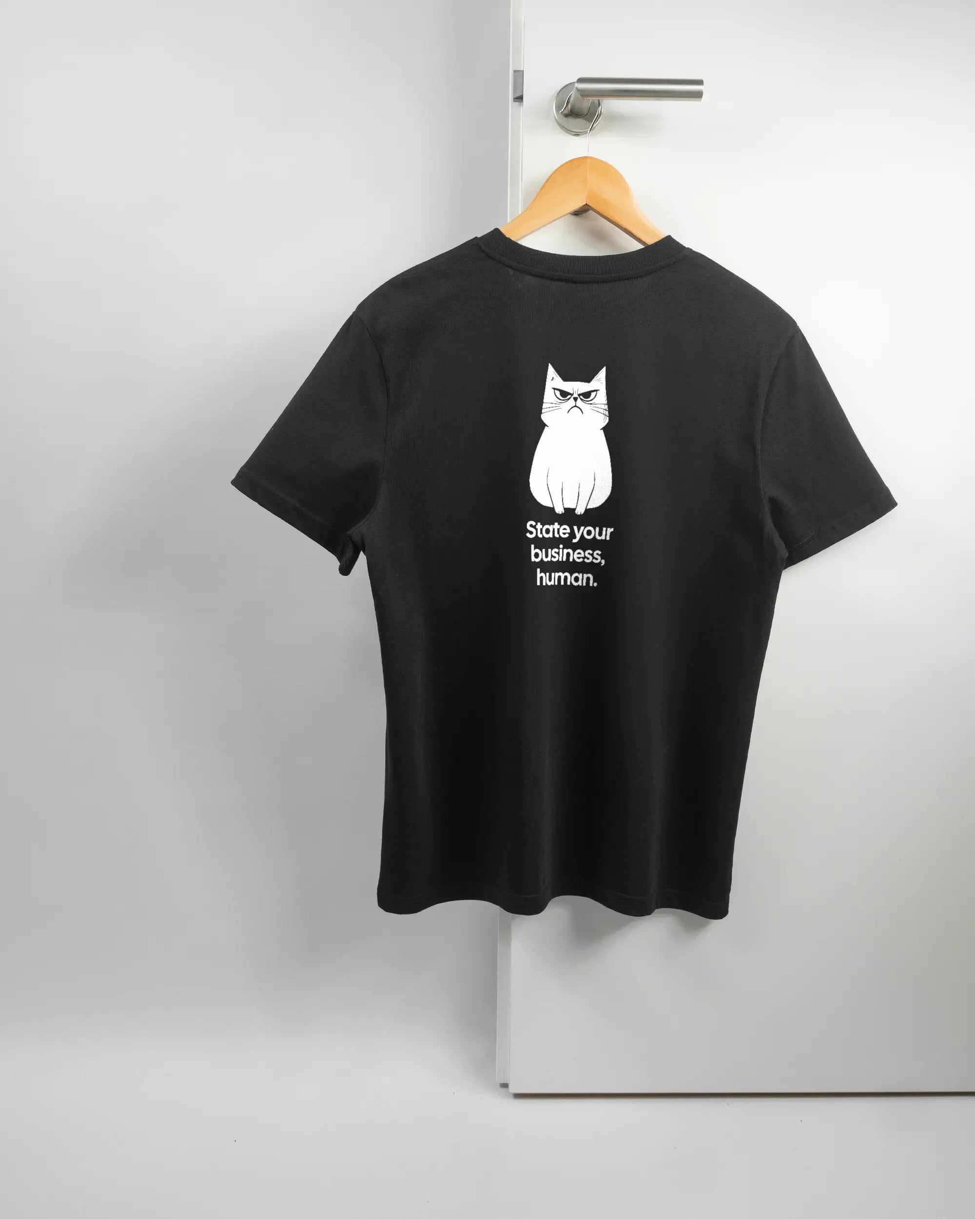Rückseite des Organic Unisex T-Shirt Casual von Maondo mit dem Design Grumpy Purr in der Farbe Black und in der Größe S auf einem Bügel an der Türklinke aufgehängt