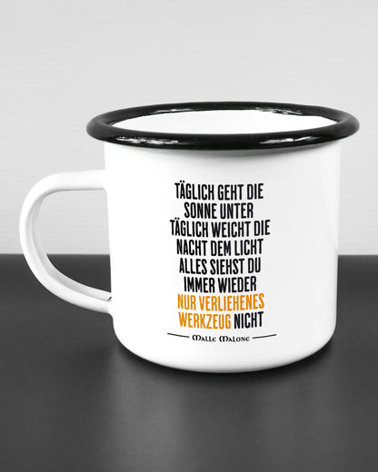Titelbild, das die linke Seite der beidseitig bedruckten Emailletasse von Maondo mit dem Design Wegzeug in der Farbe White-Black auf einem Holztisch zeigt