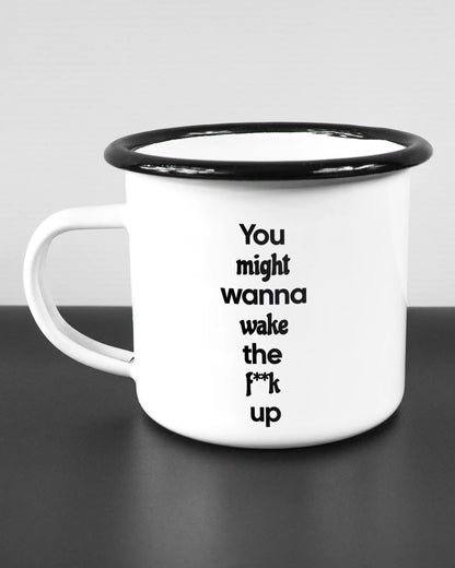 Titelbild, das die linke Seite der beidseitig bedruckten Emailletasse von Maondo mit dem Design Wanna Wake in der Farbe White-Black auf einem Holztisch zeigt