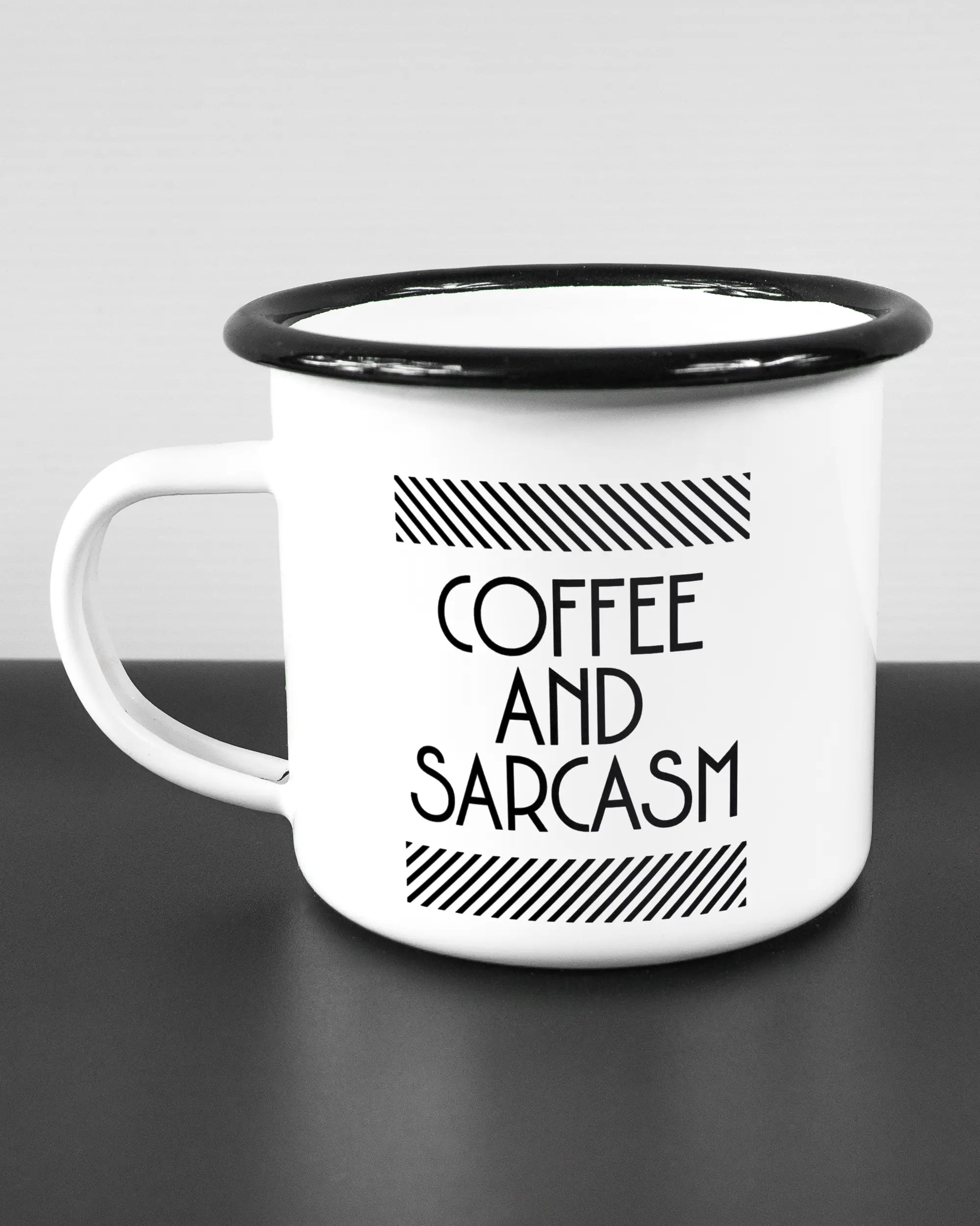 Titelbild, das die linke Seite der beidseitig bedruckten Emailletasse von Maondo mit dem Design Sarcastic Cup in der Farbe White-Black auf einem Holztisch zeigt