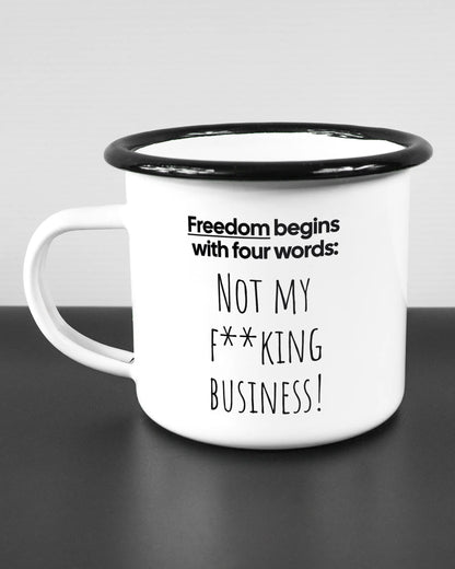 Titelbild, das die linke Seite der beidseitig bedruckten Emailletasse von Maondo mit dem Design 4 Freedom in der Farbe White-Black auf einem Holztisch zeigt