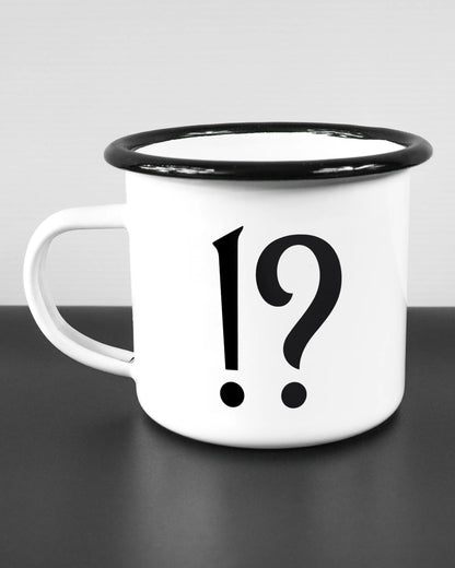 Titelbild, das die linke Seite der beidseitig bedruckten Emailletasse von Maondo mit dem Design WHAT in der Farbe White-Black auf einem Holztisch zeigt