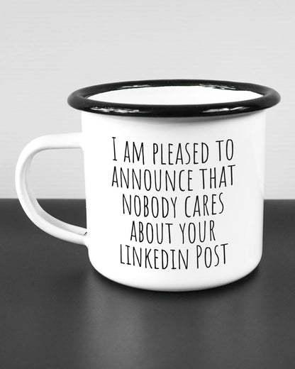 Titelbild, das die linke Seite der beidseitig bedruckten Emailletasse von Maondo mit dem Design Please Unannounce in der Farbe White-Black auf einem Holztisch zeigt