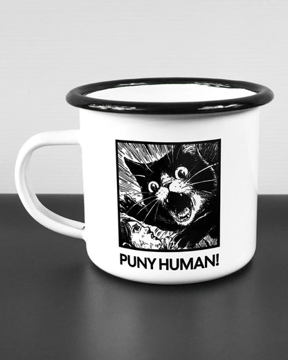 Titelbild, das die linke Seite der beidseitig bedruckten Emailletasse von Maondo mit dem Design Puny Human in der Farbe White-Black auf einem Holztisch zeigt