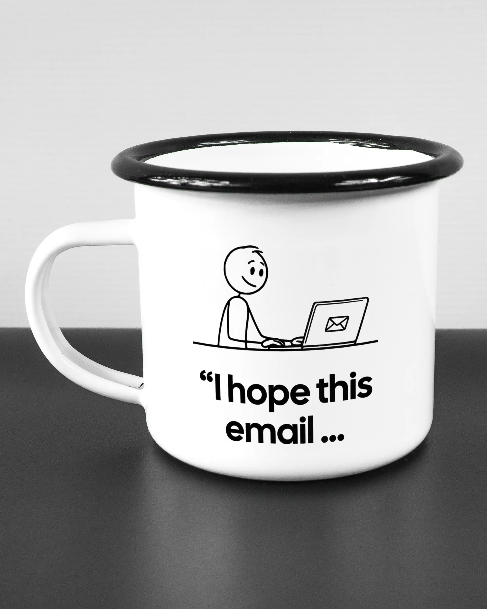 Titelbild, das die linke Seite der beidseitig bedruckten Emailletasse von Maondo mit dem Design Found me not well in der Farbe White-Black auf einem Holztisch zeigt