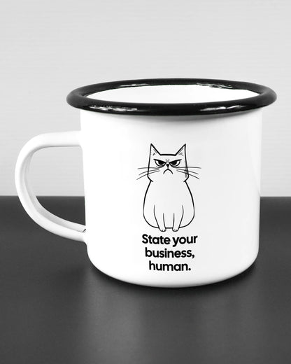 Titelbild, das die linke Seite der beidseitig bedruckten Emailletasse von Maondo mit dem Design Grumpy Purr in der Farbe White-Black auf einem Holztisch zeigt