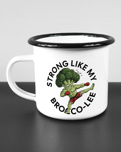 Titelbild, das die linke Seite der beidseitig bedruckten Emailletasse von Maondo mit dem Design Brocco-Lee in der Farbe White-Black auf einem Holztisch zeigt