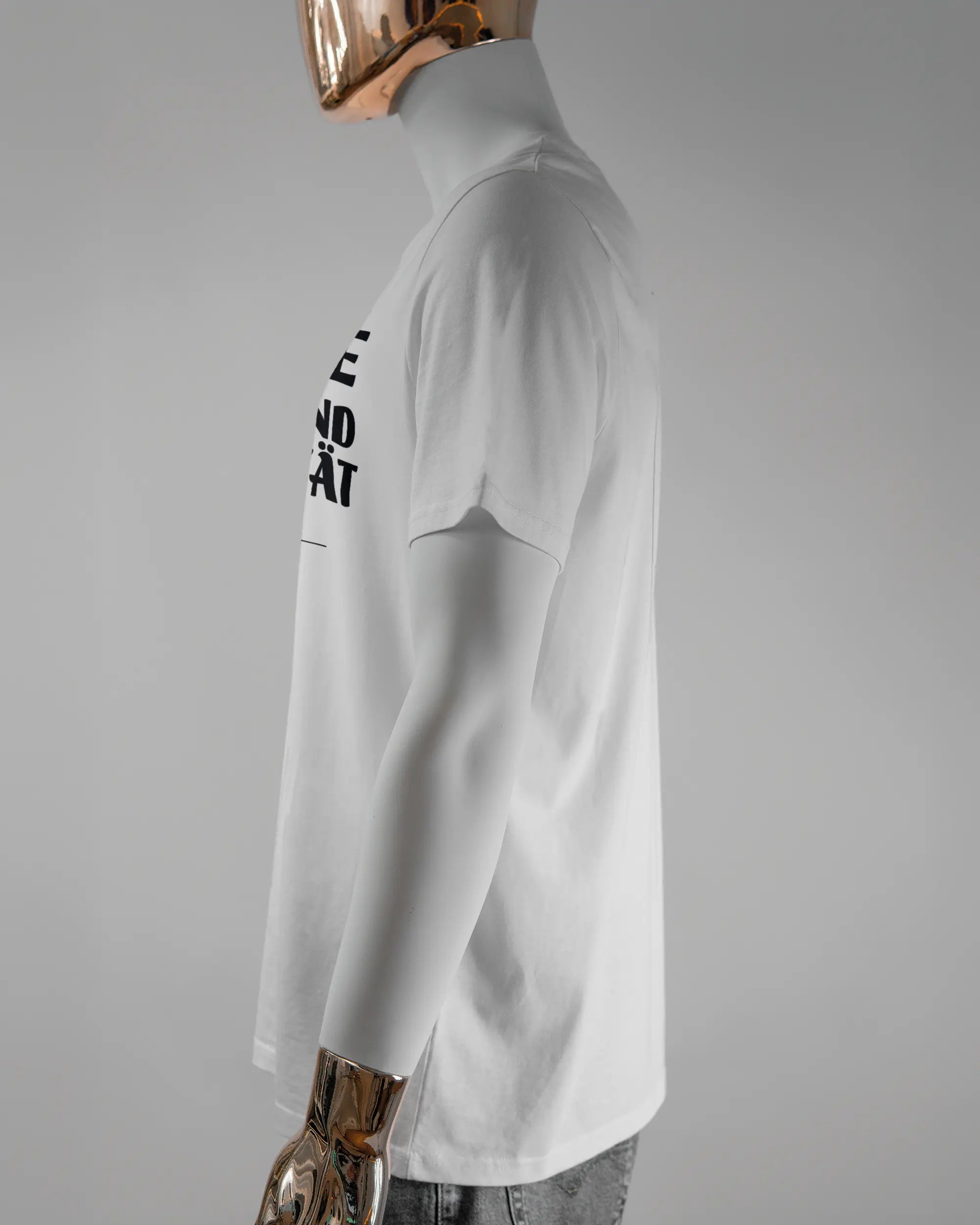 Seitenansicht des Organic Unisex T-Shirt Casual von Maondo mit dem Design Keine Eile vorne in der Farbe White und in der Größe L getragen von einer maskulinen Puppe