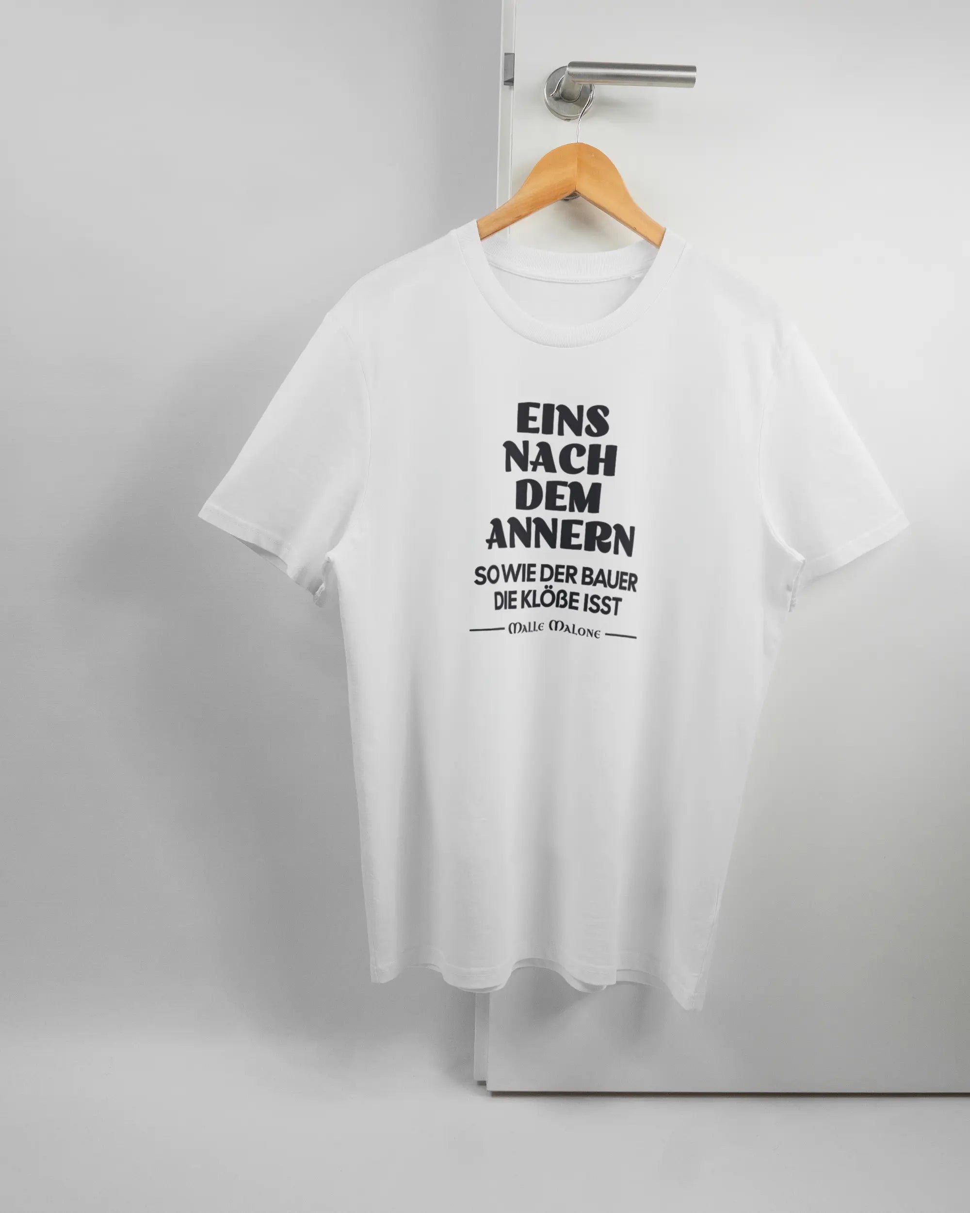 Vorderseite des Organic Unisex T-Shirt Casual von Maondo mit dem Design Eins nach dem Annern in der Farbe White und in der Größe L auf einem Bügel an der Türklinke aufgehängt