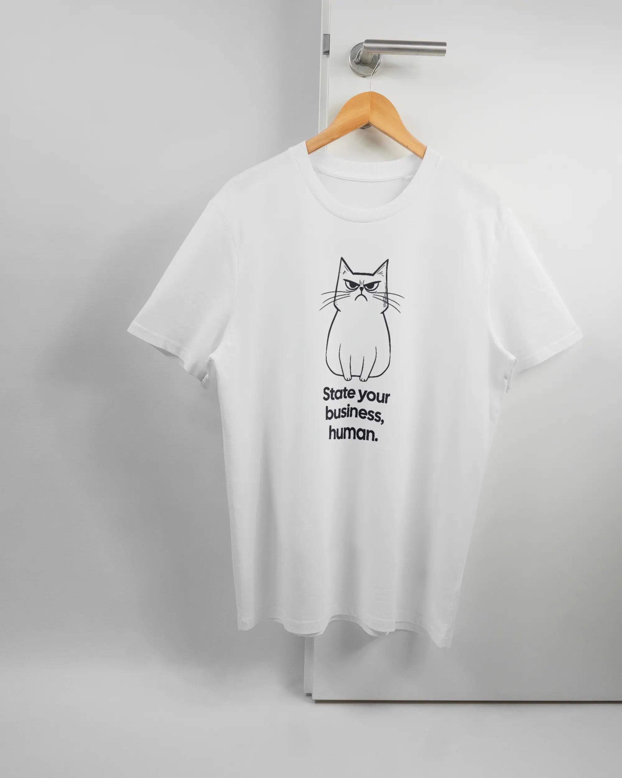 Vorderseite des Organic Unisex T-Shirt Casual von Maondo mit dem Design Grumpy Purr in der Farbe White und in der Größe L auf einem Bügel an der Türklinke aufgehängt