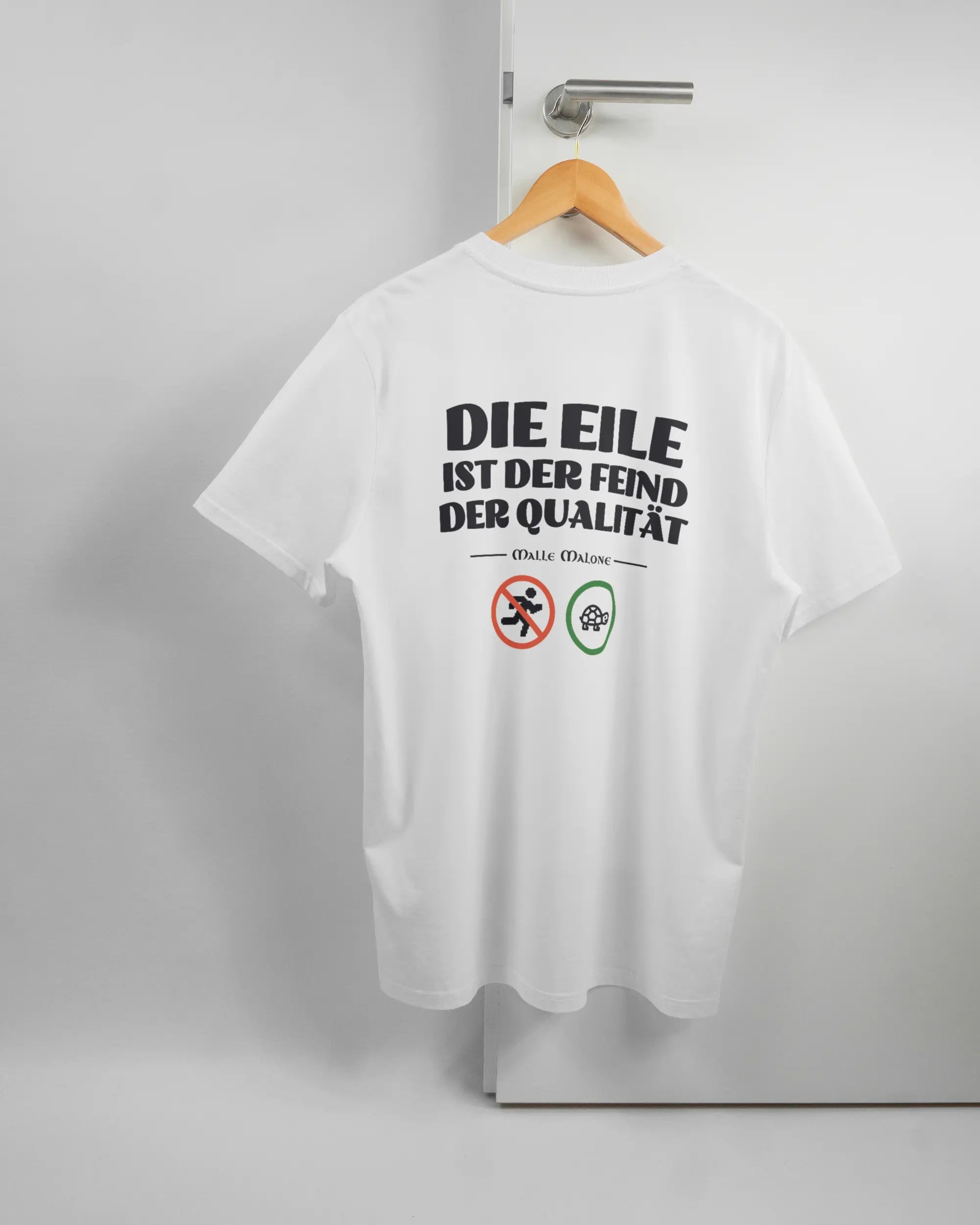 Rückseite des Organic Unisex T-Shirt Casual von Maondo mit dem Design Keine Eile in der Farbe White und in der Größe L auf einem Bügel an der Türklinke aufgehängt