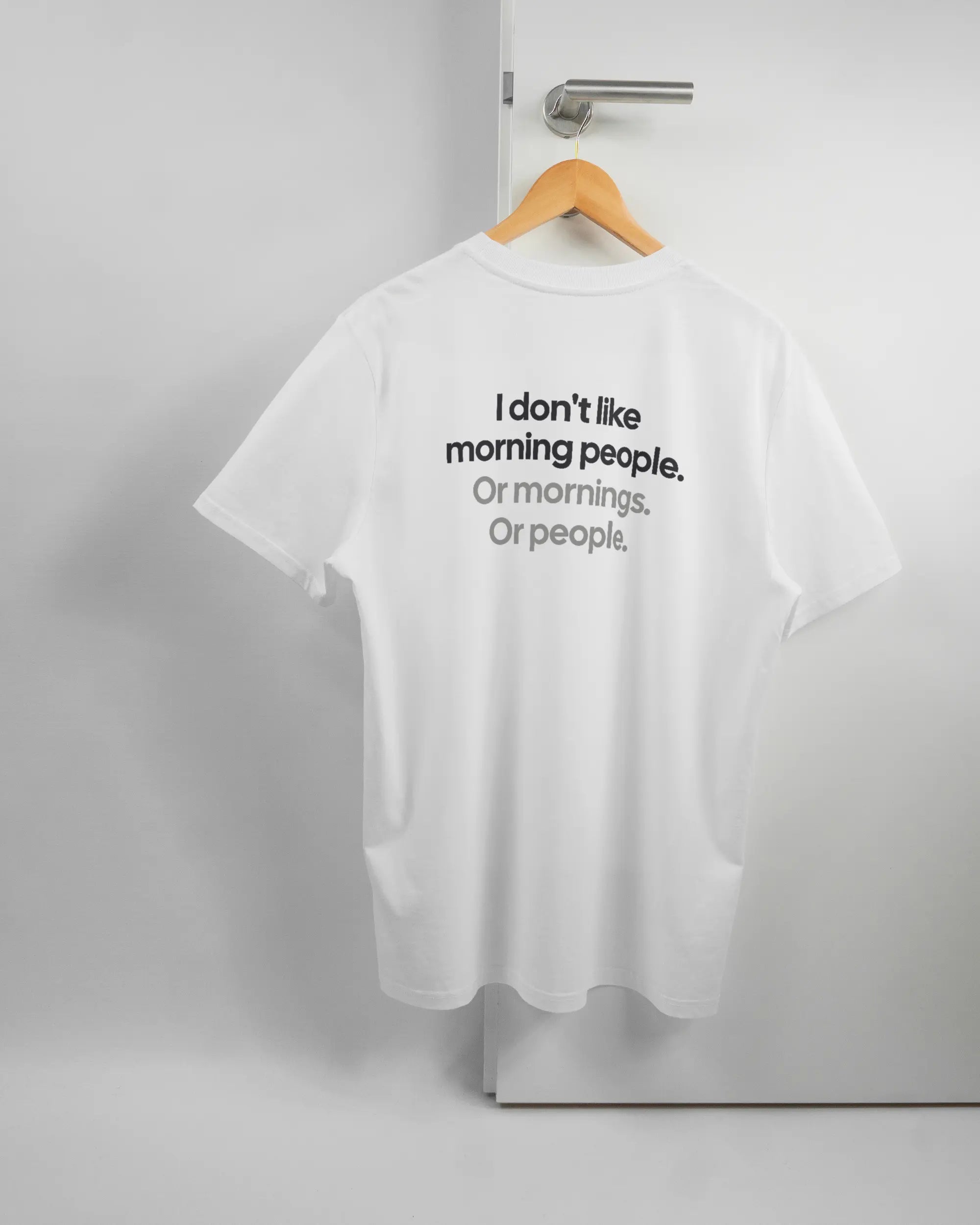 Rückseite des Organic Unisex T-Shirt Casual von Maondo mit dem Design Morning Person in der Farbe White und in der Größe L auf einem Bügel an der Türklinke aufgehängt