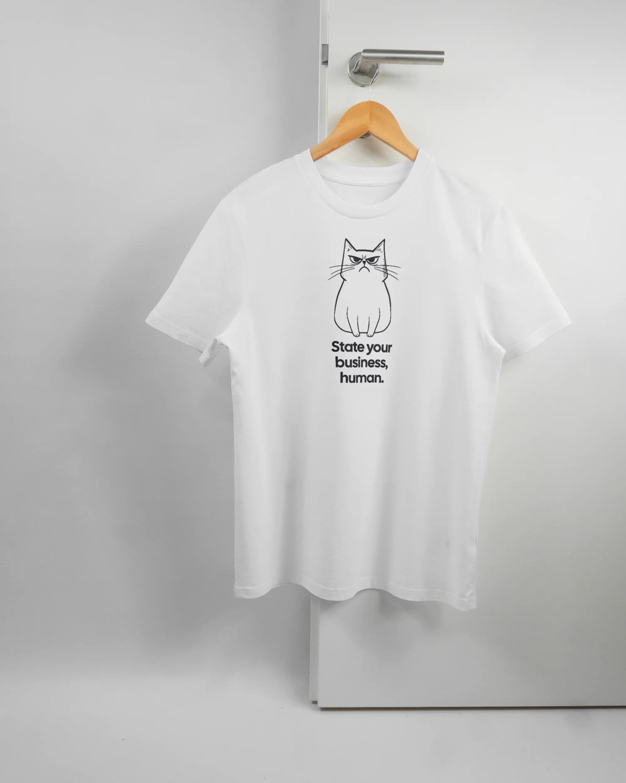 Vorderseite des Organic Unisex T-Shirt Casual von Maondo mit dem Design Grumpy Purr in der Farbe White und in der Größe S auf einem Bügel an der Türklinke aufgehängt