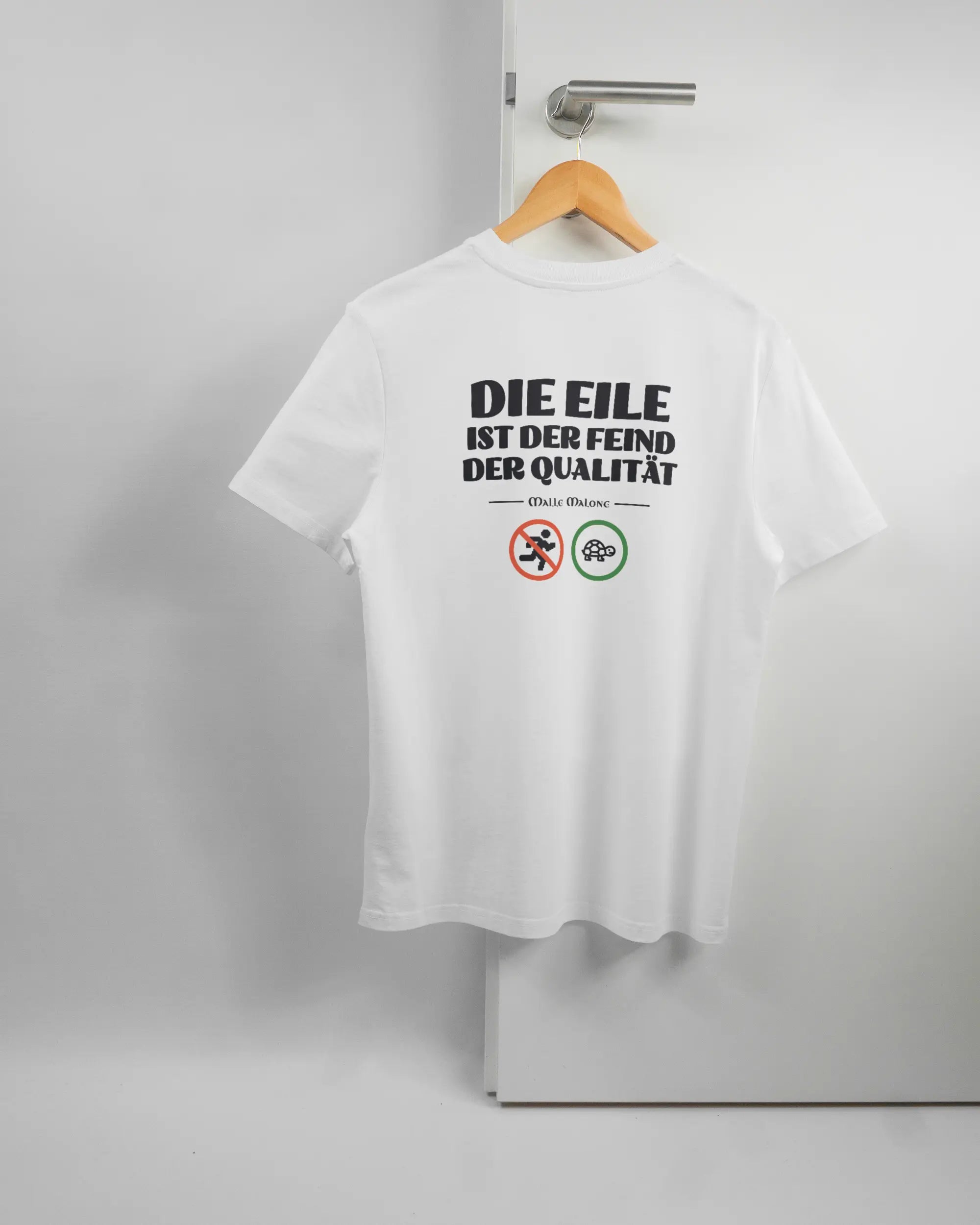 Rückseite des Organic Unisex T-Shirt Casual von Maondo mit dem Design Keine Eile in der Farbe White und in der Größe S auf einem Bügel an der Türklinke aufgehängt