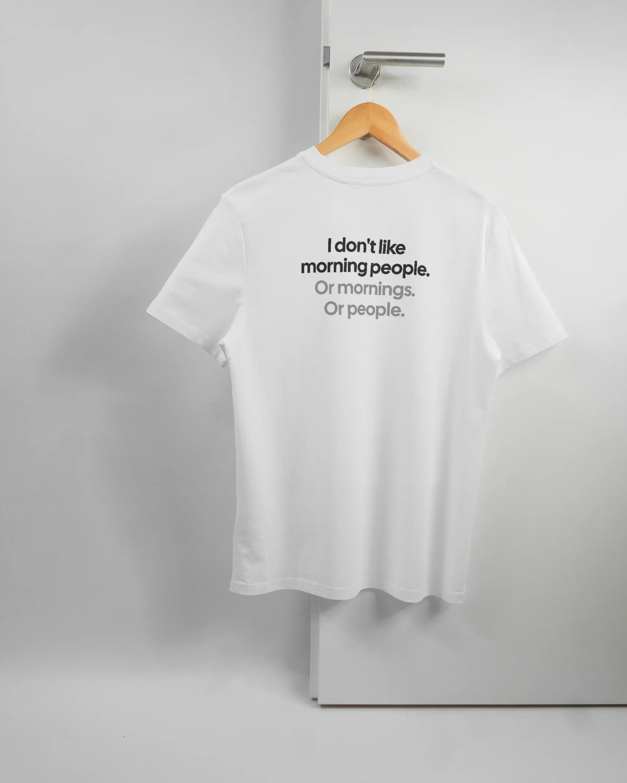 Rückseite des Organic Unisex T-Shirt Casual von Maondo mit dem Design Morning Person in der Farbe White und in der Größe S auf einem Bügel an der Türklinke aufgehängt