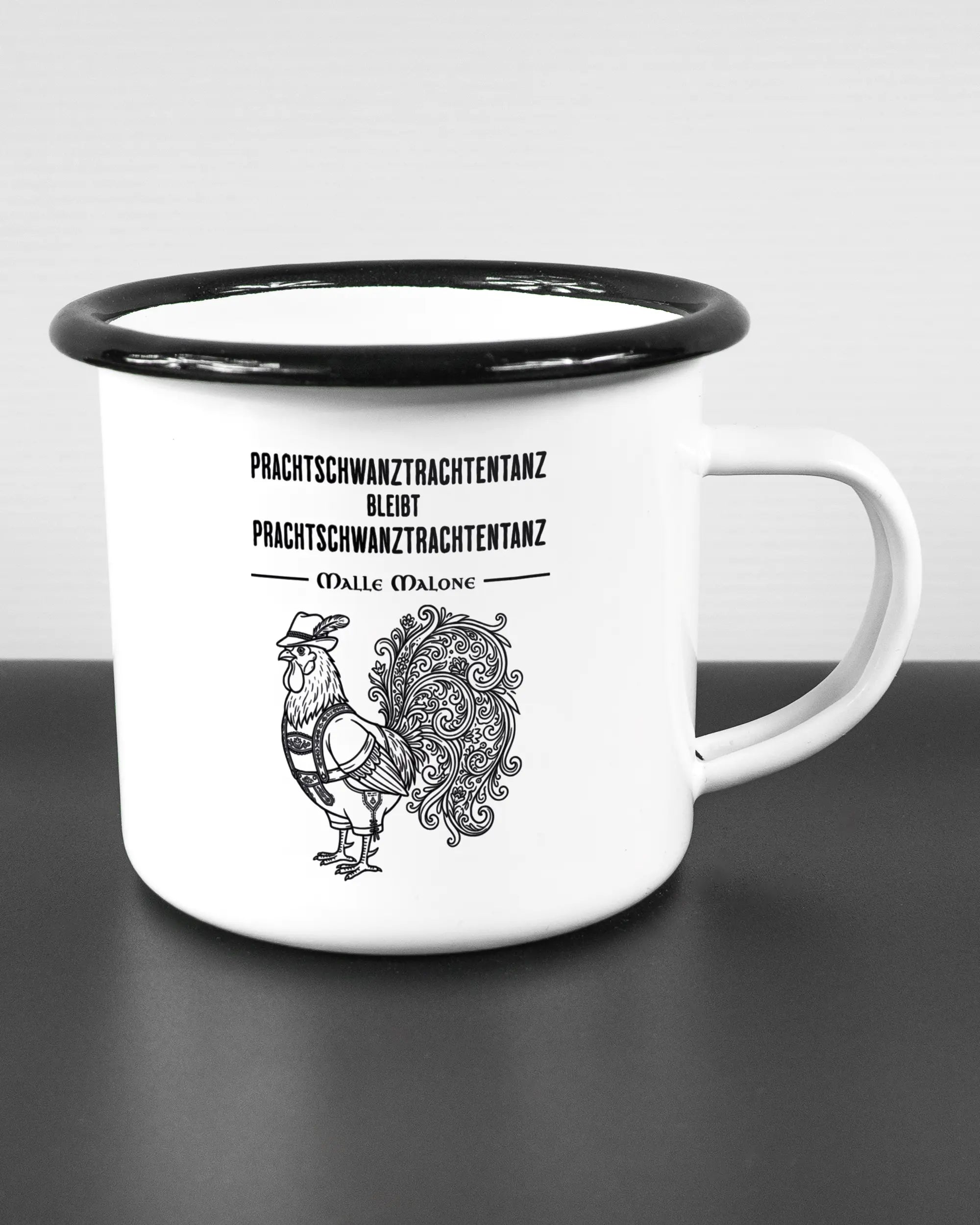 Alternativbild, das die rechte Seite der beidseitig bedruckten Emailletasse von Maondo mit dem Design Trachtentanz in der Farbe White-Black auf einem Holztisch zeigt