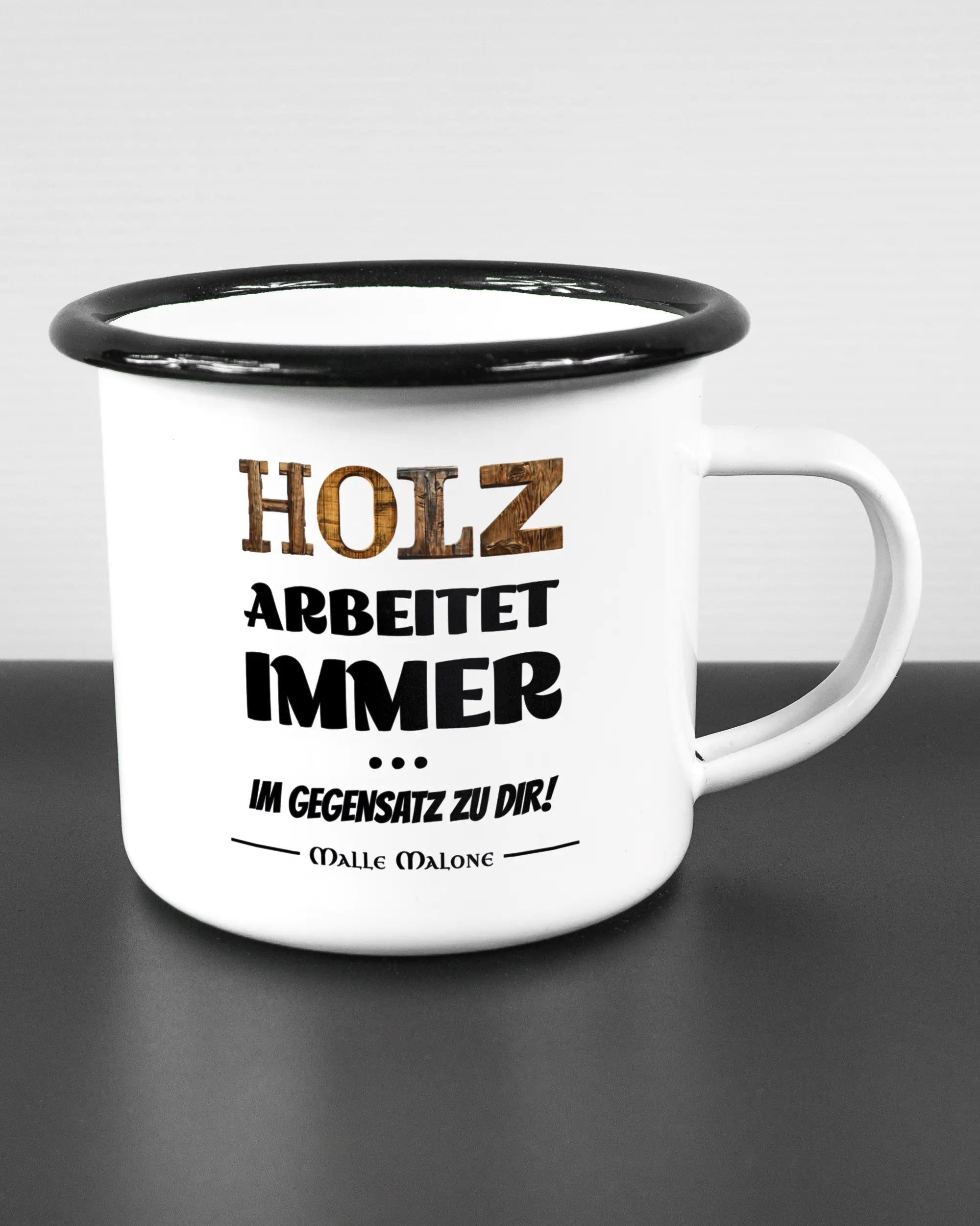 Alternativbild, das die rechte Seite der beidseitig bedruckten Emailletasse von Maondo mit dem Design Holzarbeit in der Farbe White-Black auf einem Holztisch zeigt