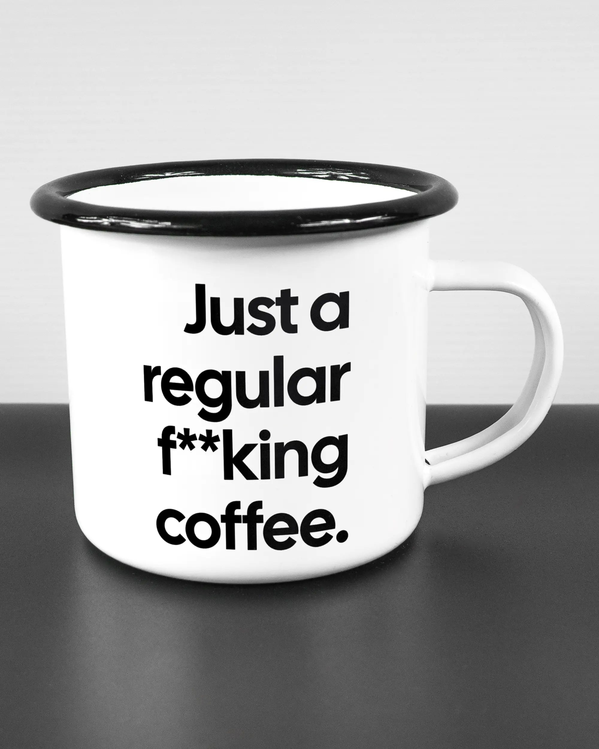 Alternativbild, das die rechte Seite der beidseitig bedruckten Emailletasse von Maondo mit dem Design Regular Coffee in der Farbe White-Black auf einem Holztisch zeigt