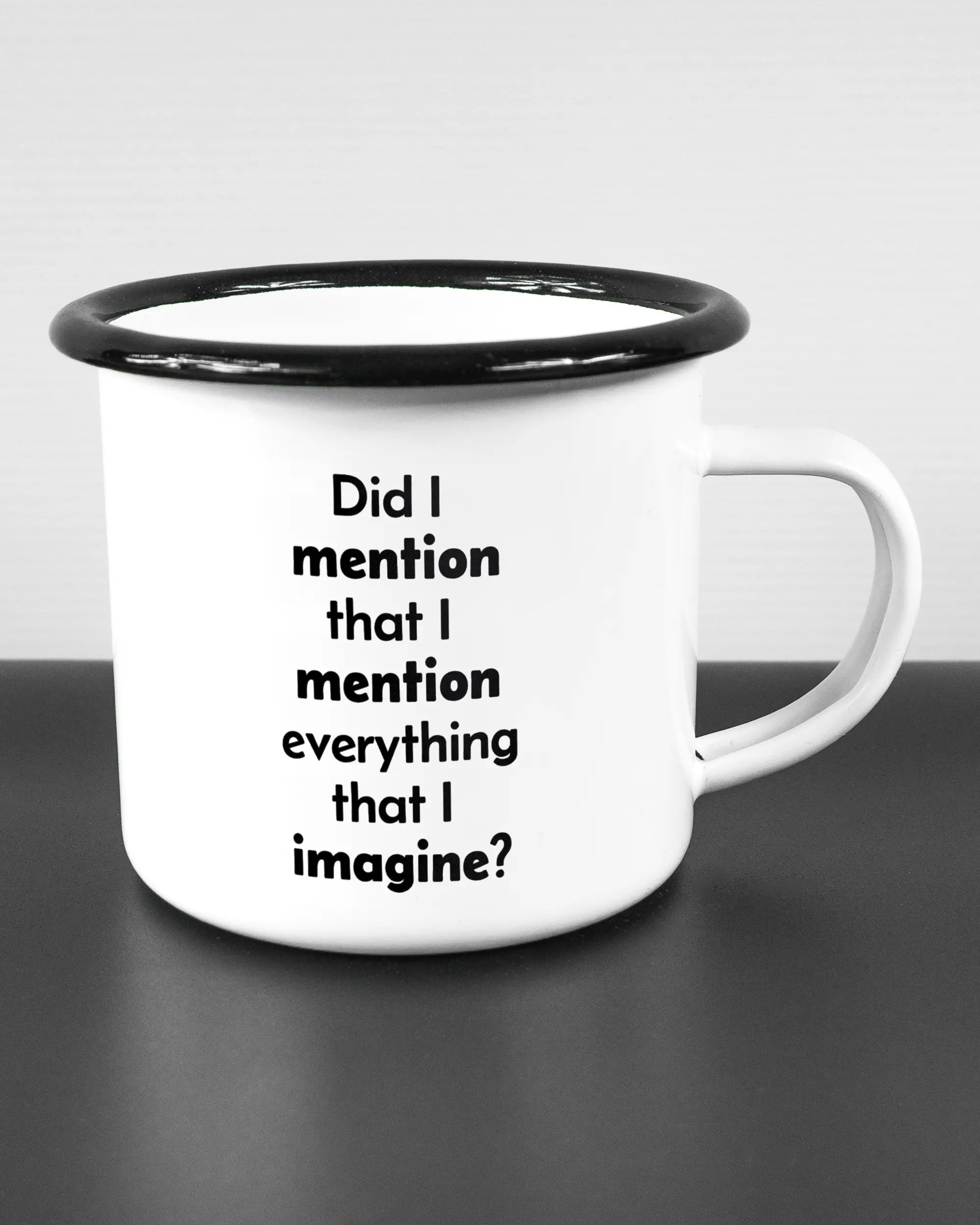 Alternativbild, das die rechte Seite der beidseitig bedruckten Emailletasse von Maondo mit dem Design Did I mention in der Farbe White-Black auf einem Holztisch zeigt