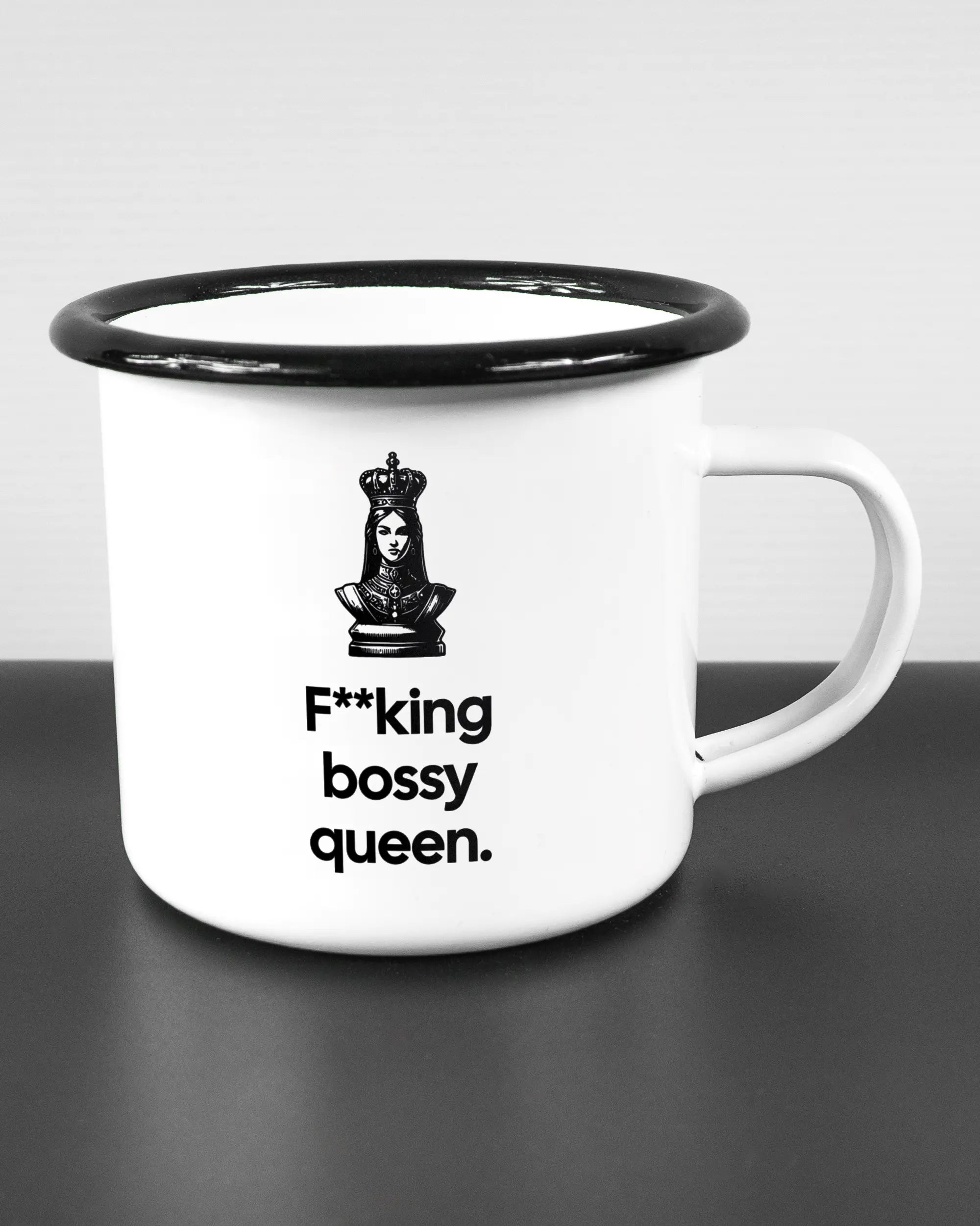 Alternativbild, das die rechte Seite der beidseitig bedruckten Emailletasse von Maondo mit dem Design Bossy Queen in der Farbe White-Black auf einem Holztisch zeigt