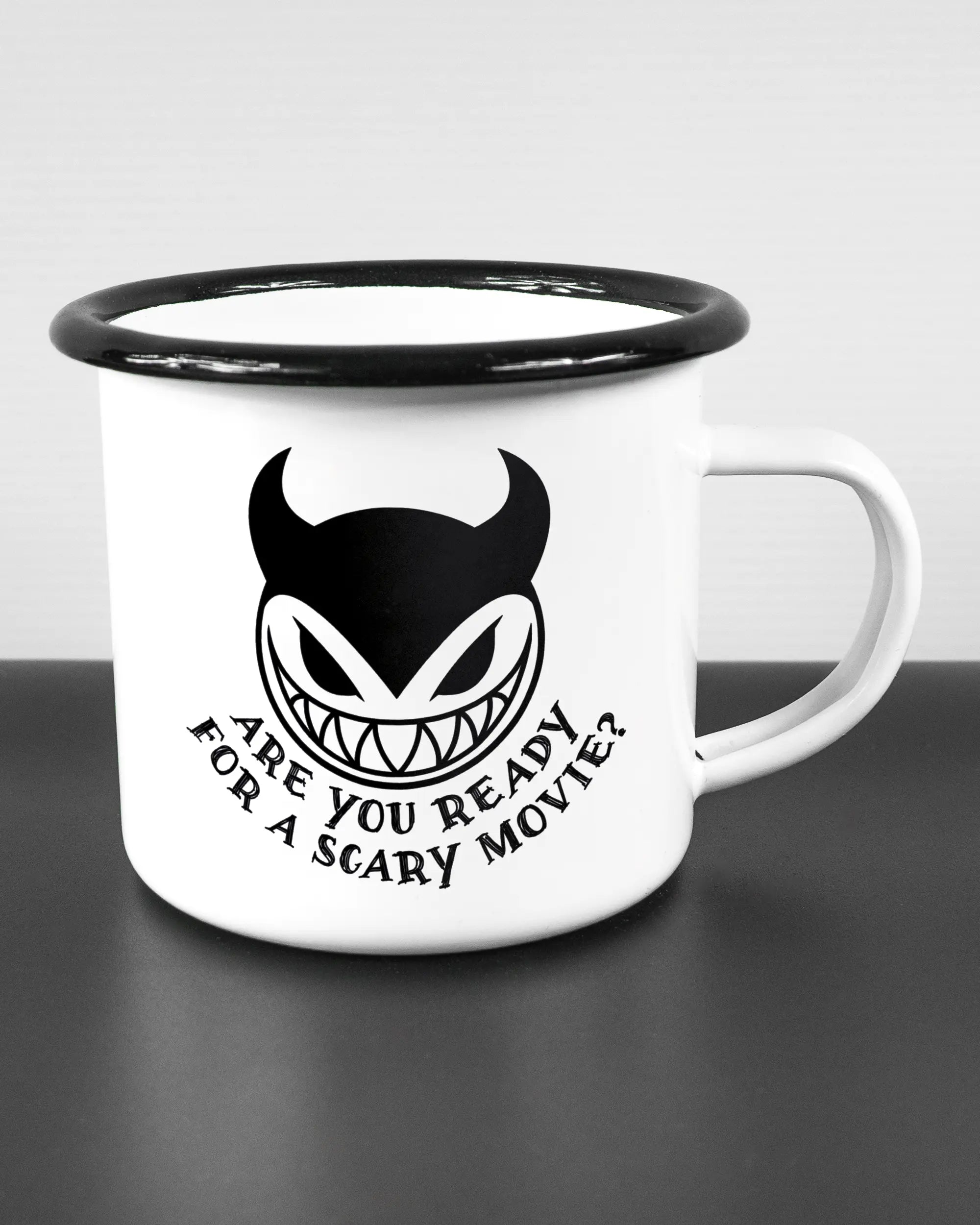 Alternativbild, das die rechte Seite der beidseitig bedruckten Emailletasse von Maondo mit dem Design Scary Movie in der Farbe White-Black auf einem Holztisch zeigt