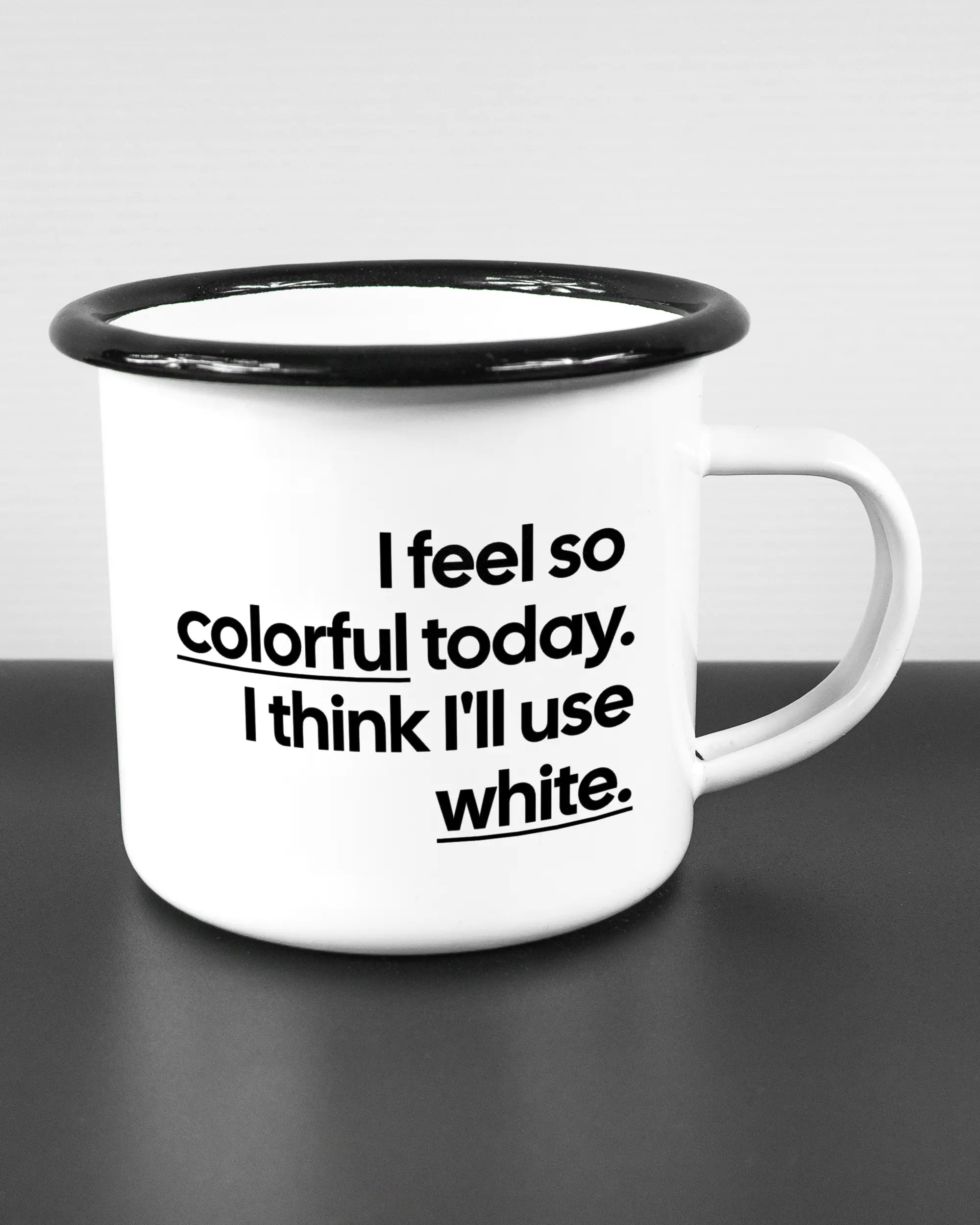 Alternativbild, das die rechte Seite der beidseitig bedruckten Emailletasse von Maondo mit dem Design Colorful Day in der Farbe White-Black auf einem Holztisch zeigt