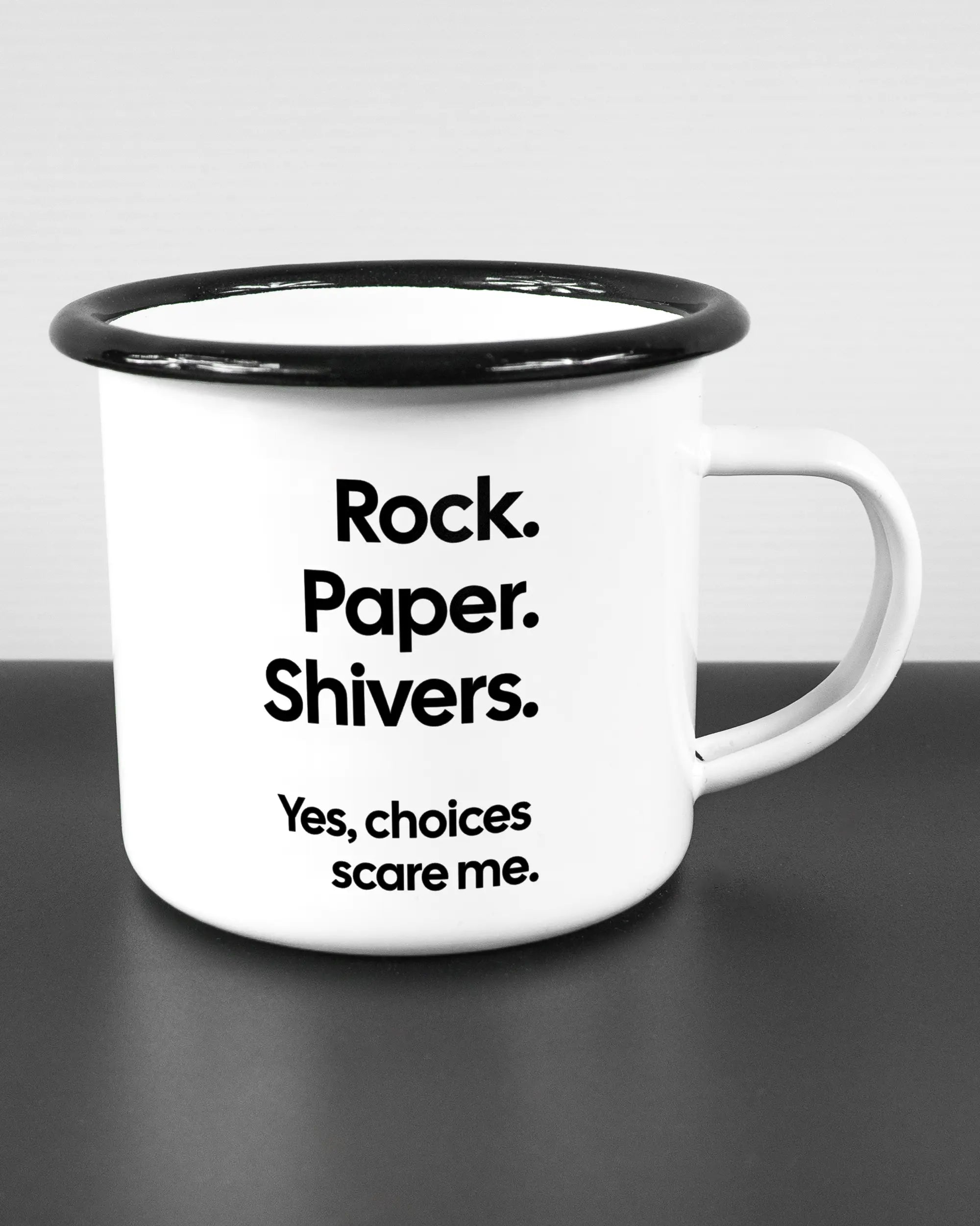 Alternativbild, das die rechte Seite der beidseitig bedruckten Emailletasse von Maondo mit dem Design Rock Paper Shivers in der Farbe White-Black auf einem Holztisch zeigt