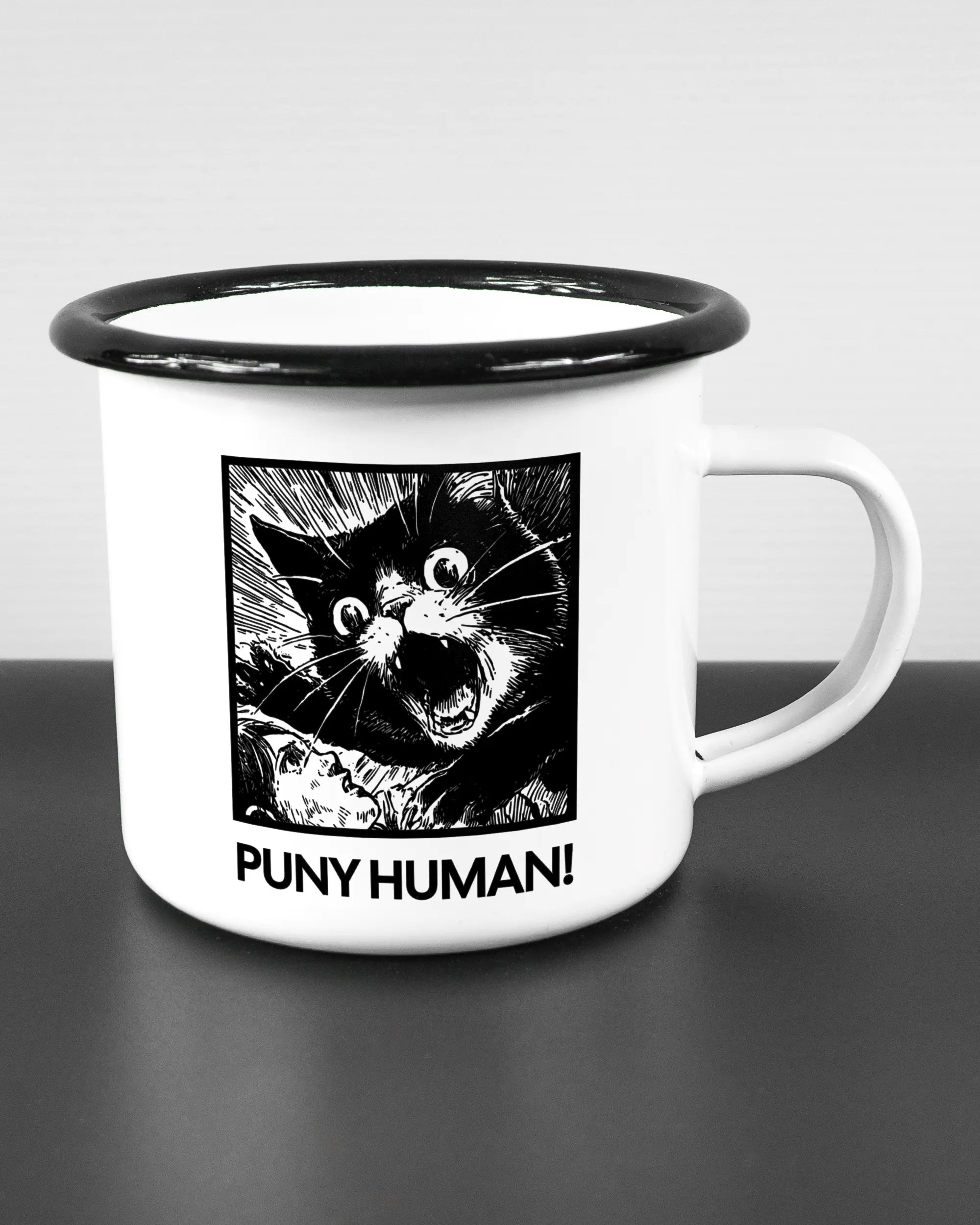 Alternativbild, das die rechte Seite der beidseitig bedruckten Emailletasse von Maondo mit dem Design Puny Human in der Farbe White-Black auf einem Holztisch zeigt