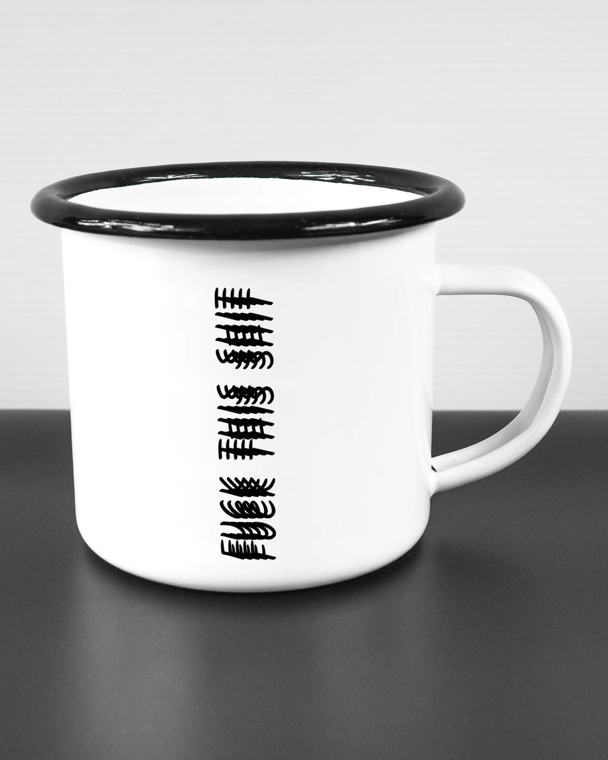 Alternativbild, das die rechte Seite der beidseitig bedruckten Emailletasse von Maondo mit dem Design Hidden Message in der Farbe White-Black auf einem Holztisch zeigt