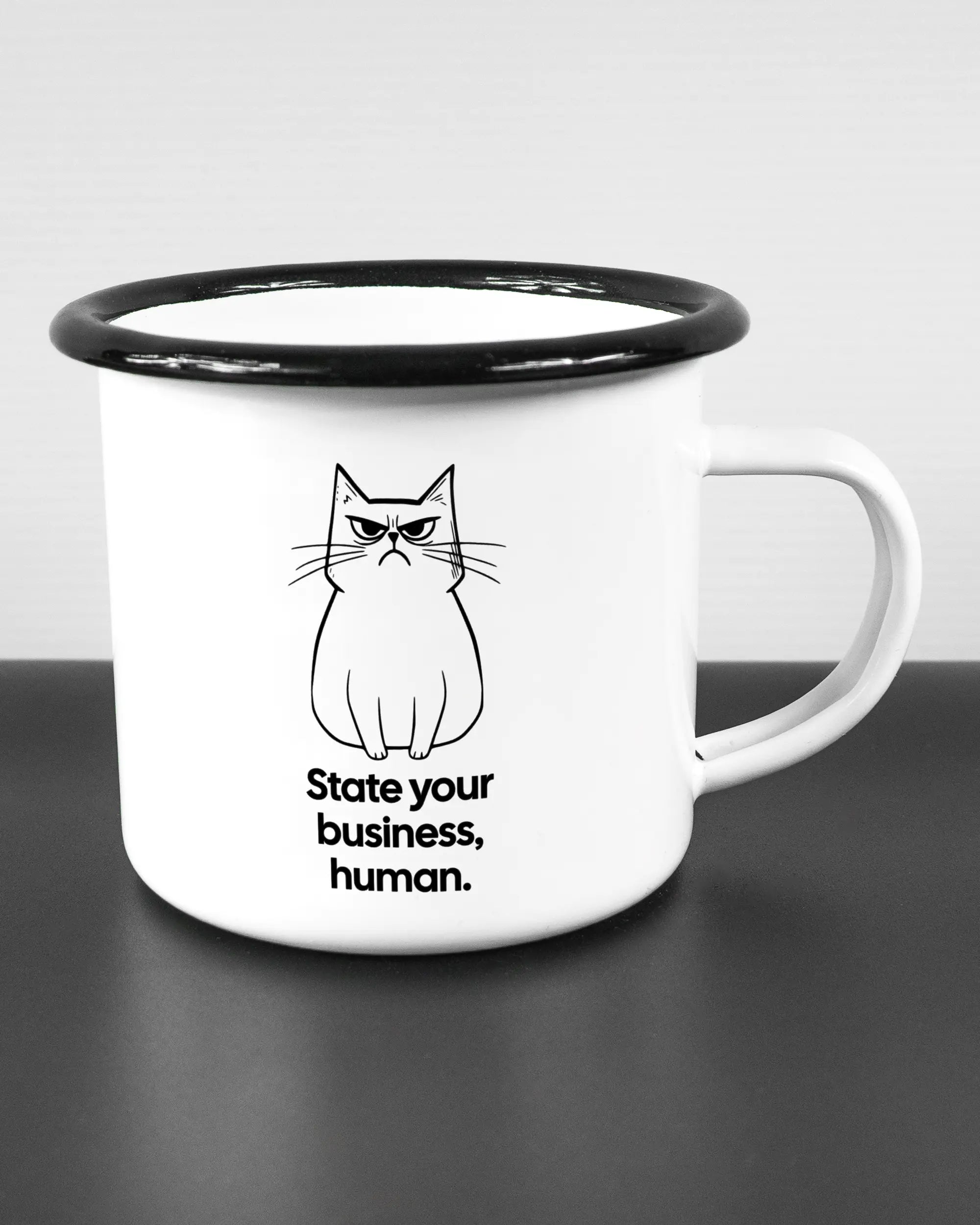 Alternativbild, das die rechte Seite der beidseitig bedruckten Emailletasse von Maondo mit dem Design Grumpy Purr in der Farbe White-Black auf einem Holztisch zeigt