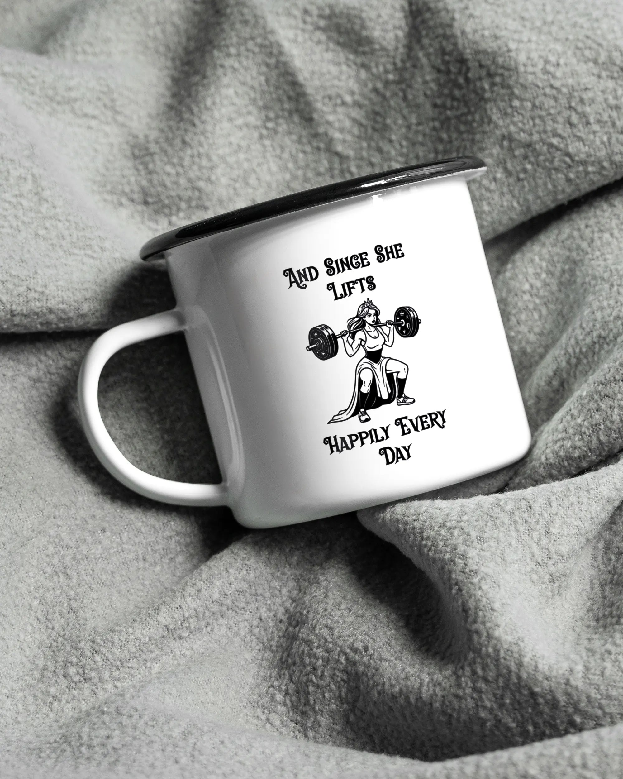 Aufnahme, die die linke Seite der beidseitig bedruckten Emailletasse von Maondo auf einer flauschigen Fließdecke mit dem Design Princess Lift in der Farbe White-Black zeigt