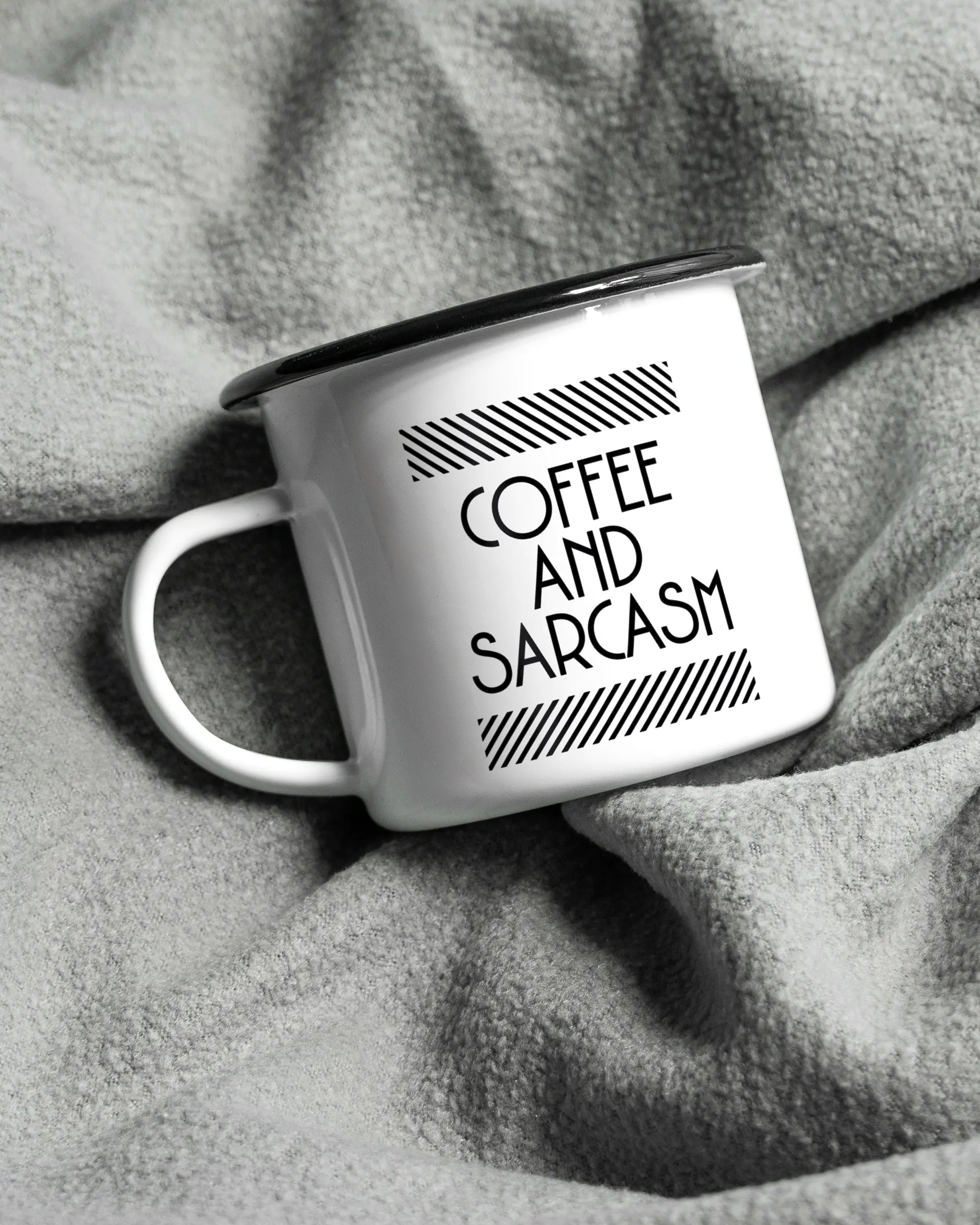 Aufnahme, die die linke Seite der beidseitig bedruckten Emailletasse von Maondo auf einer flauschigen Fließdecke mit dem Design Sarcastic Cup in der Farbe White-Black zeigt