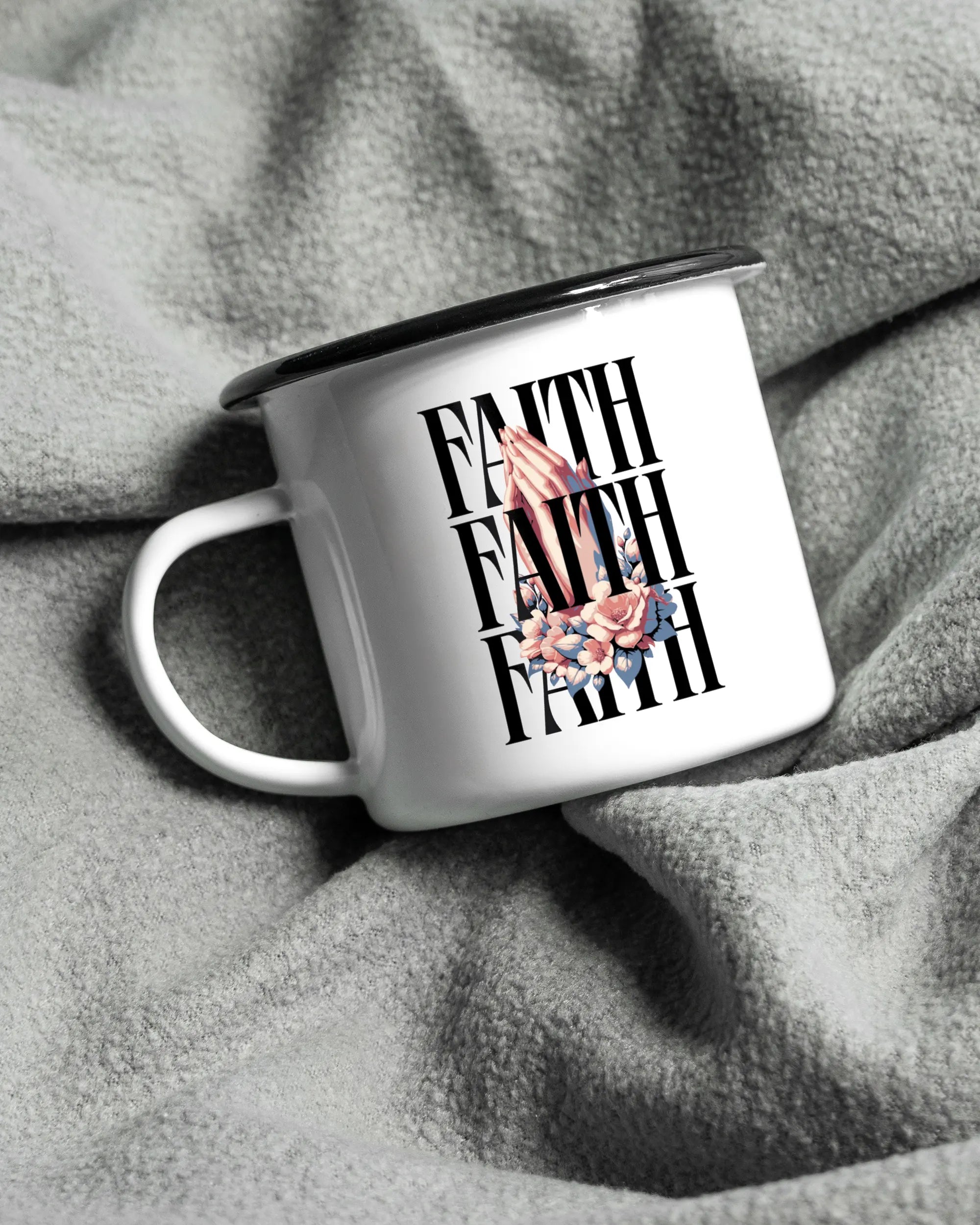 Aufnahme, die die linke Seite der beidseitig bedruckten Emailletasse von Maondo auf einer flauschigen Fließdecke mit dem Design Faith X3 in der Farbe White-Black zeigt