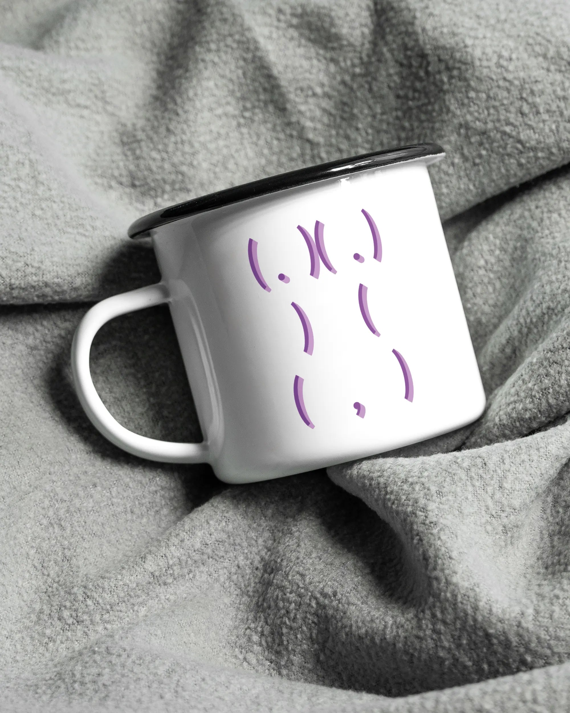 Aufnahme, die die linke Seite der beidseitig bedruckten Emailletasse von Maondo auf einer flauschigen Fließdecke mit dem Design Body Language in der Farbe White-Black zeigt