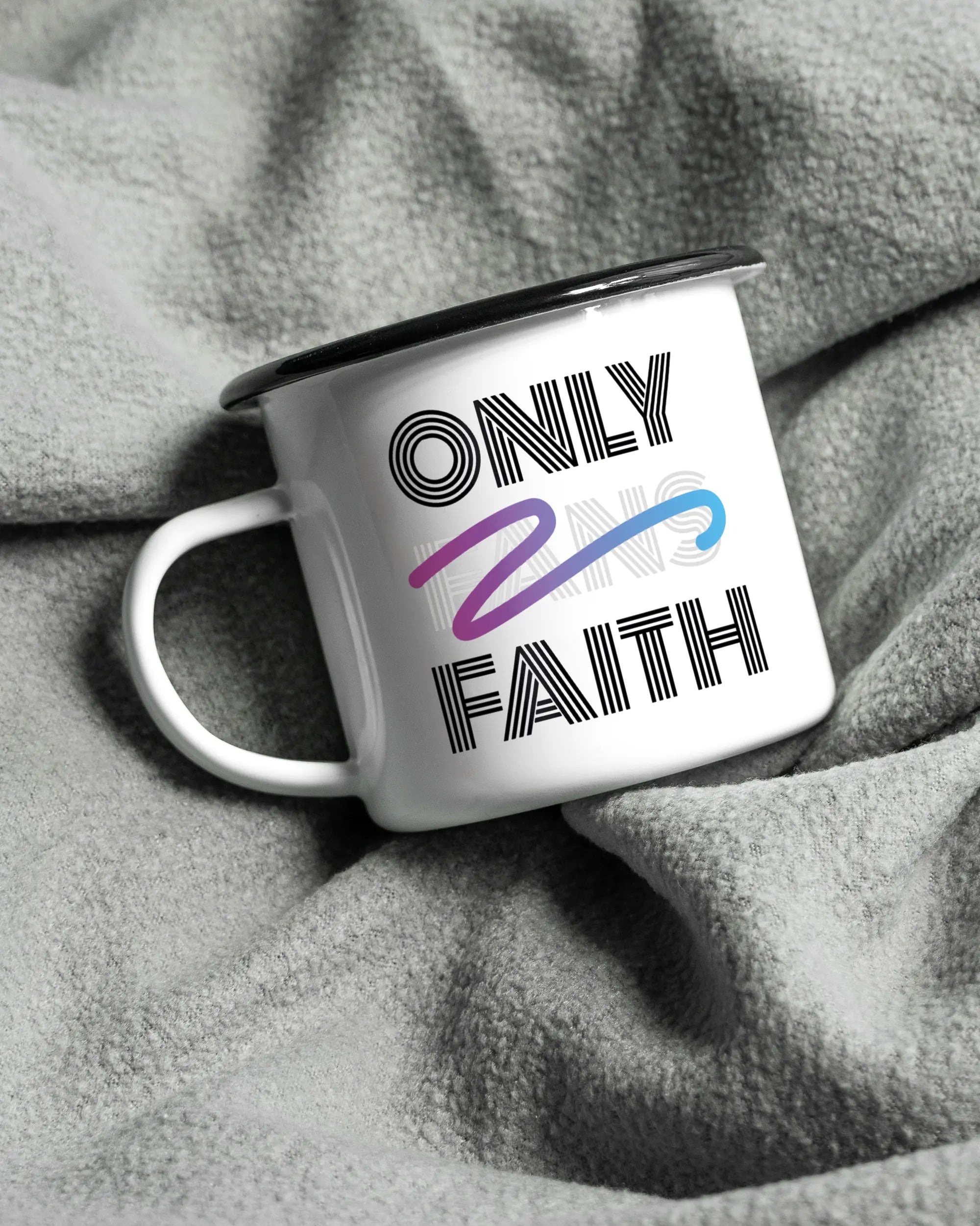 Aufnahme, die die linke Seite der beidseitig bedruckten Emailletasse von Maondo auf einer flauschigen Fließdecke mit dem Design Only Faith in der Farbe White-Black zeigt