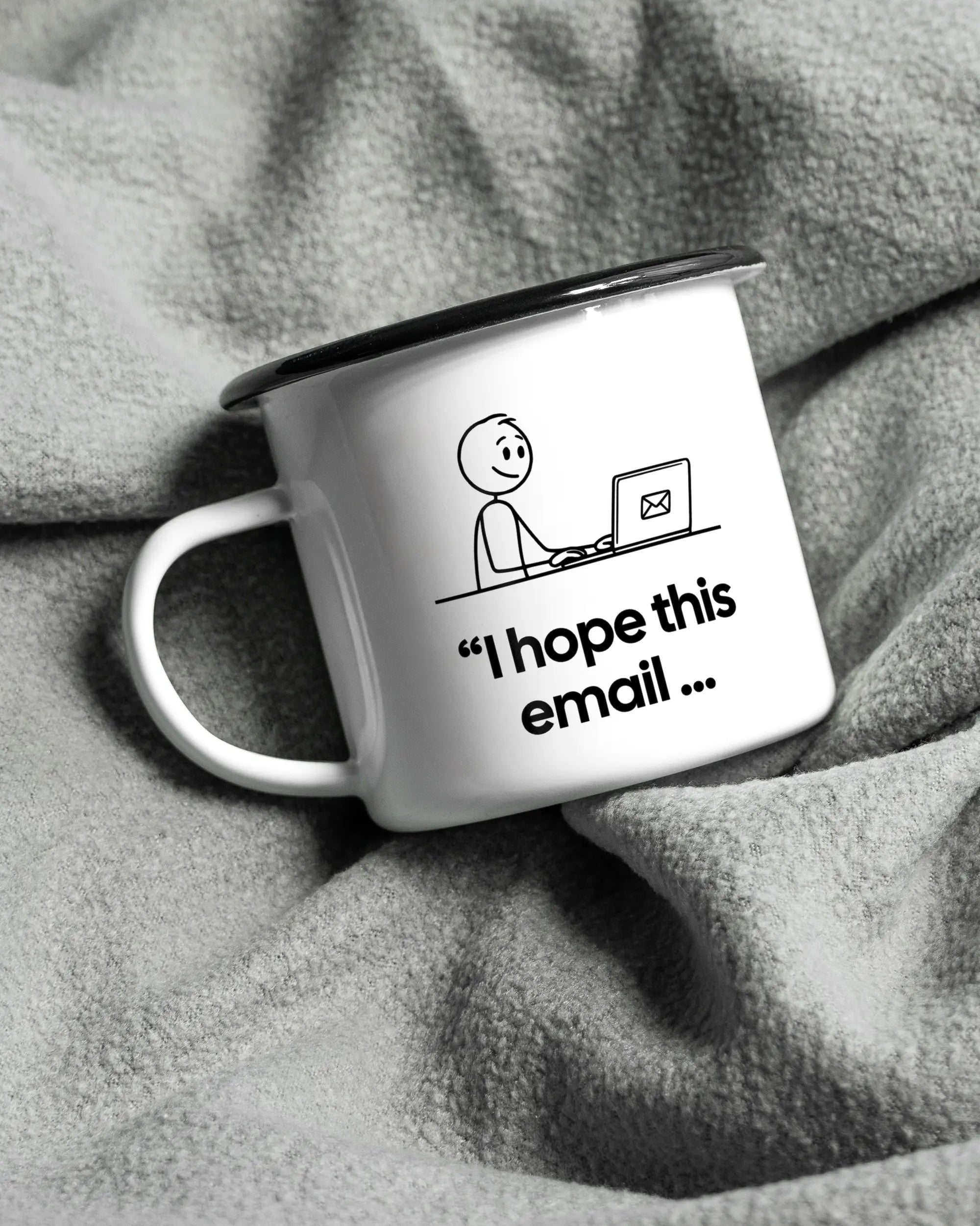 Aufnahme, die die linke Seite der beidseitig bedruckten Emailletasse von Maondo auf einer flauschigen Fließdecke mit dem Design Found me not well in der Farbe White-Black zeigt