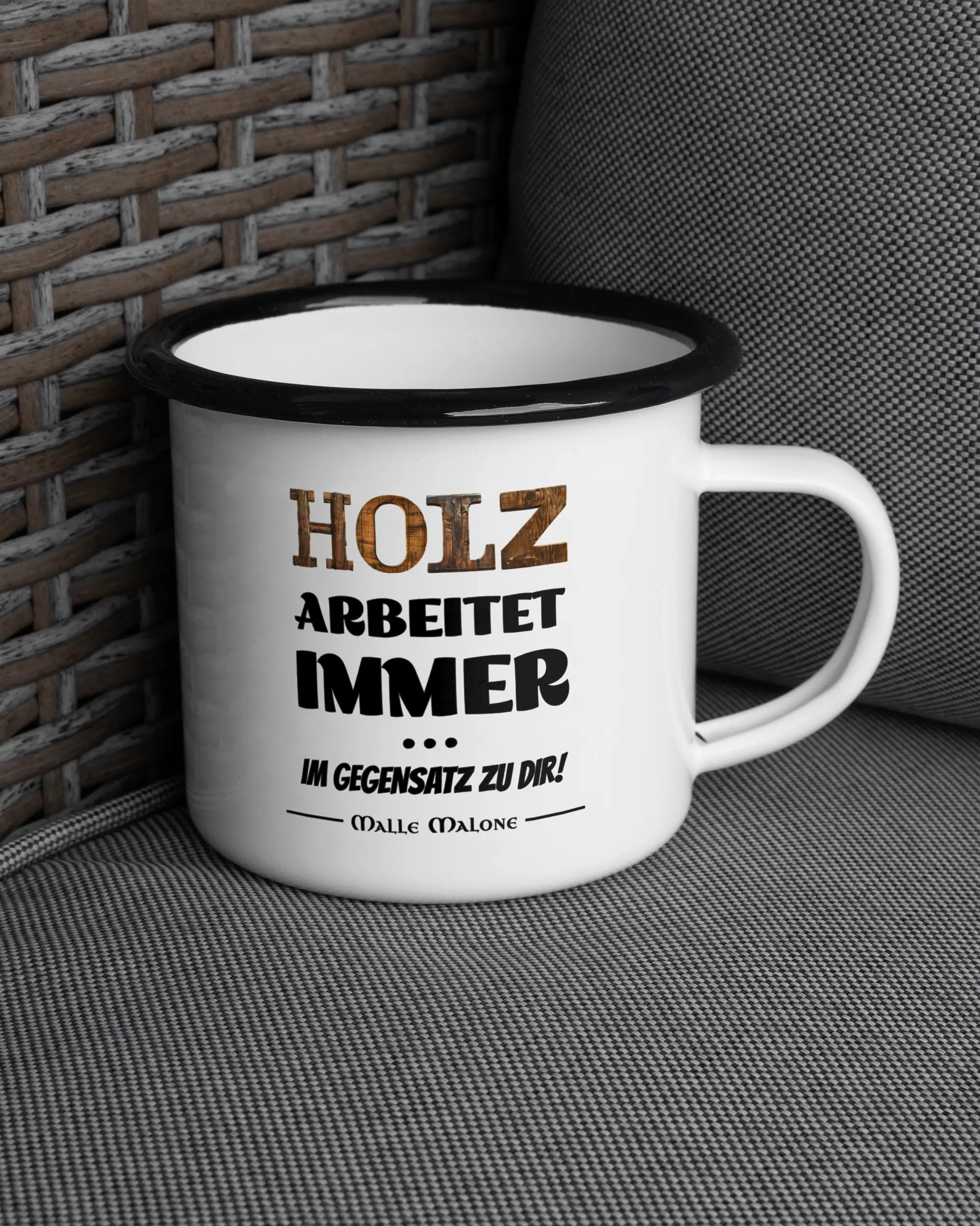 Ansicht der rechten Seite der beidseitig bedruckten Emailletasse von Maondo auf einem Balkonmöbel bzw. Campingstuhl mit dem Design Holzarbeit in der Farbe White-Black