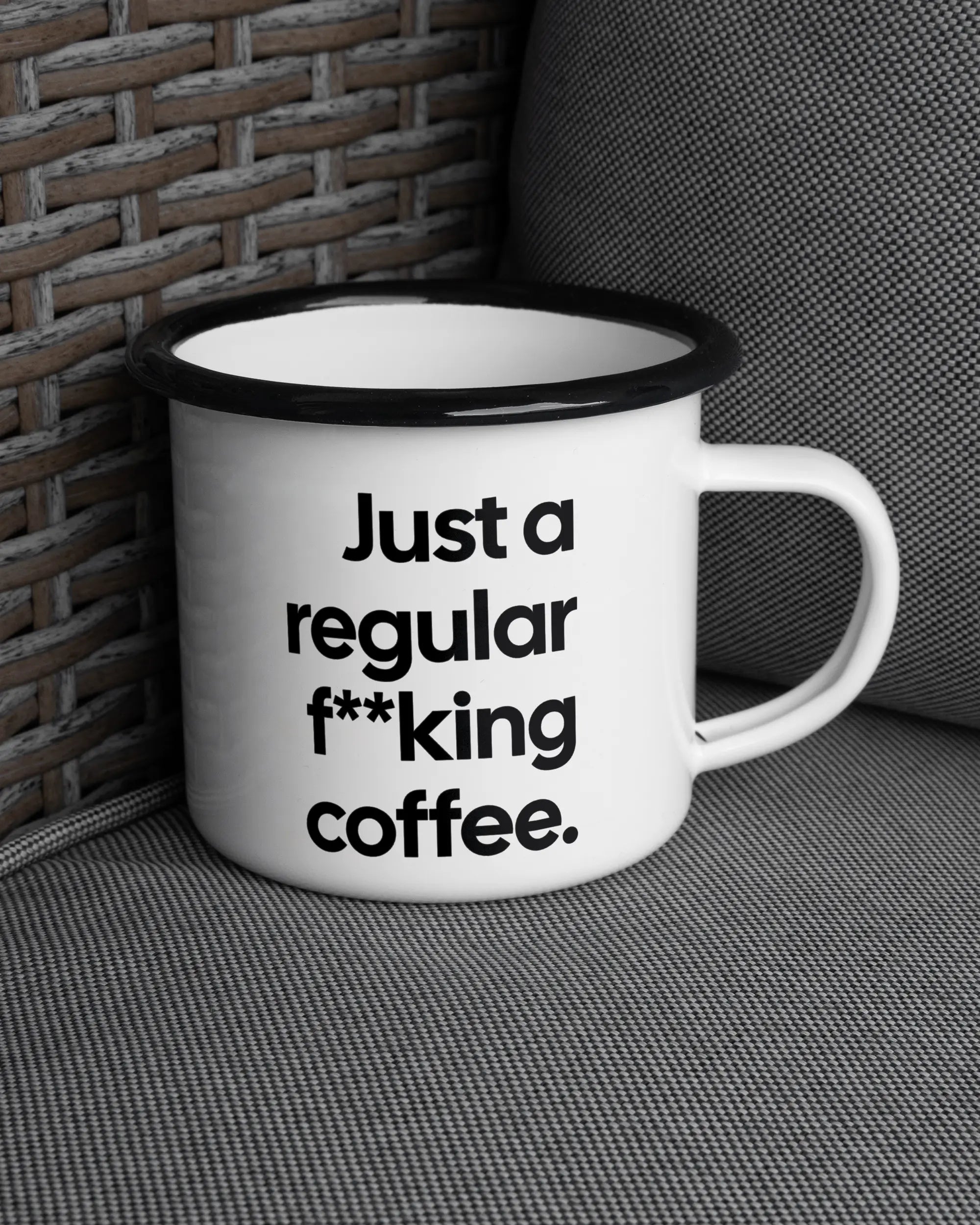 Ansicht der rechten Seite der beidseitig bedruckten Emailletasse von Maondo auf einem Balkonmöbel bzw. Campingstuhl mit dem Design Regular Coffee in der Farbe White-Black