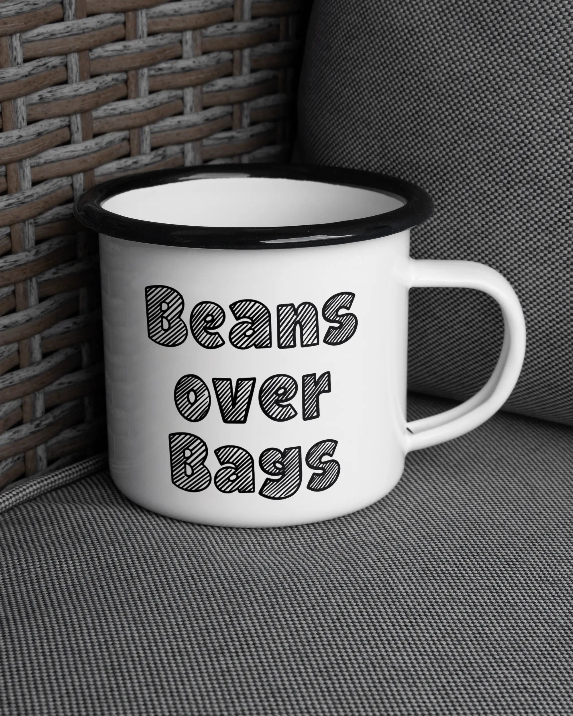 Ansicht der rechten Seite der beidseitig bedruckten Emailletasse von Maondo auf einem Balkonmöbel bzw. Campingstuhl mit dem Design Beans over Bags in der Farbe White-Black