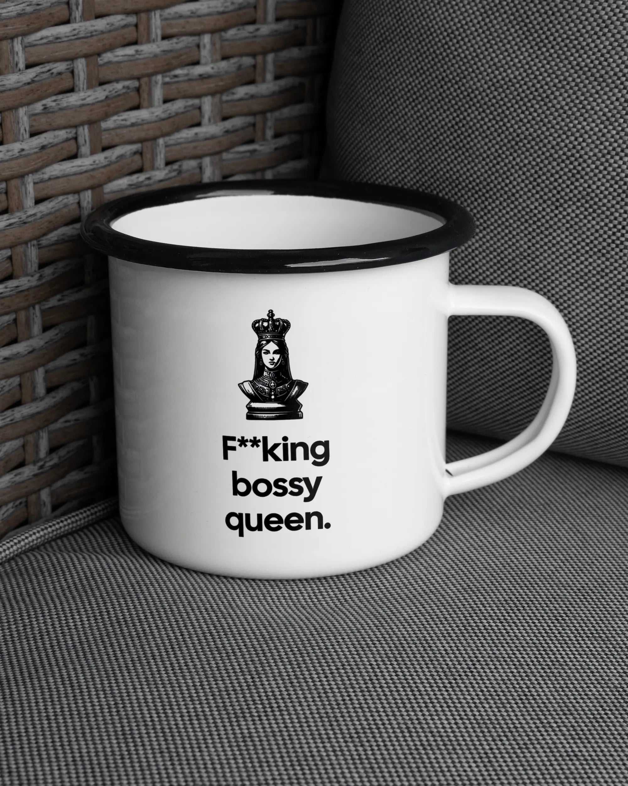 Ansicht der rechten Seite der beidseitig bedruckten Emailletasse von Maondo auf einem Balkonmöbel bzw. Campingstuhl mit dem Design Bossy Queen in der Farbe White-Black