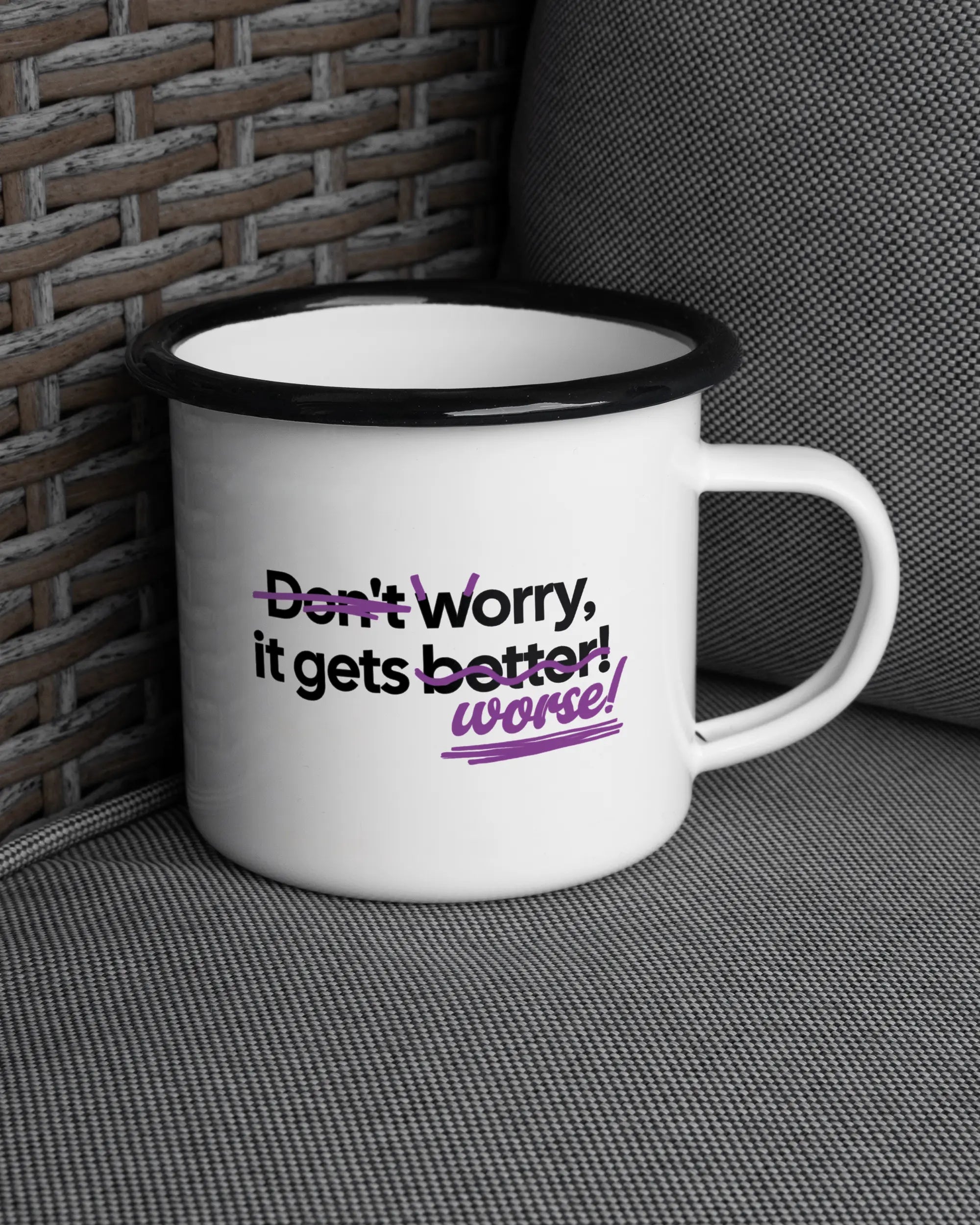 Ansicht der rechten Seite der beidseitig bedruckten Emailletasse von Maondo auf einem Balkonmöbel bzw. Campingstuhl mit dem Design Worry Worse in der Farbe White-Black