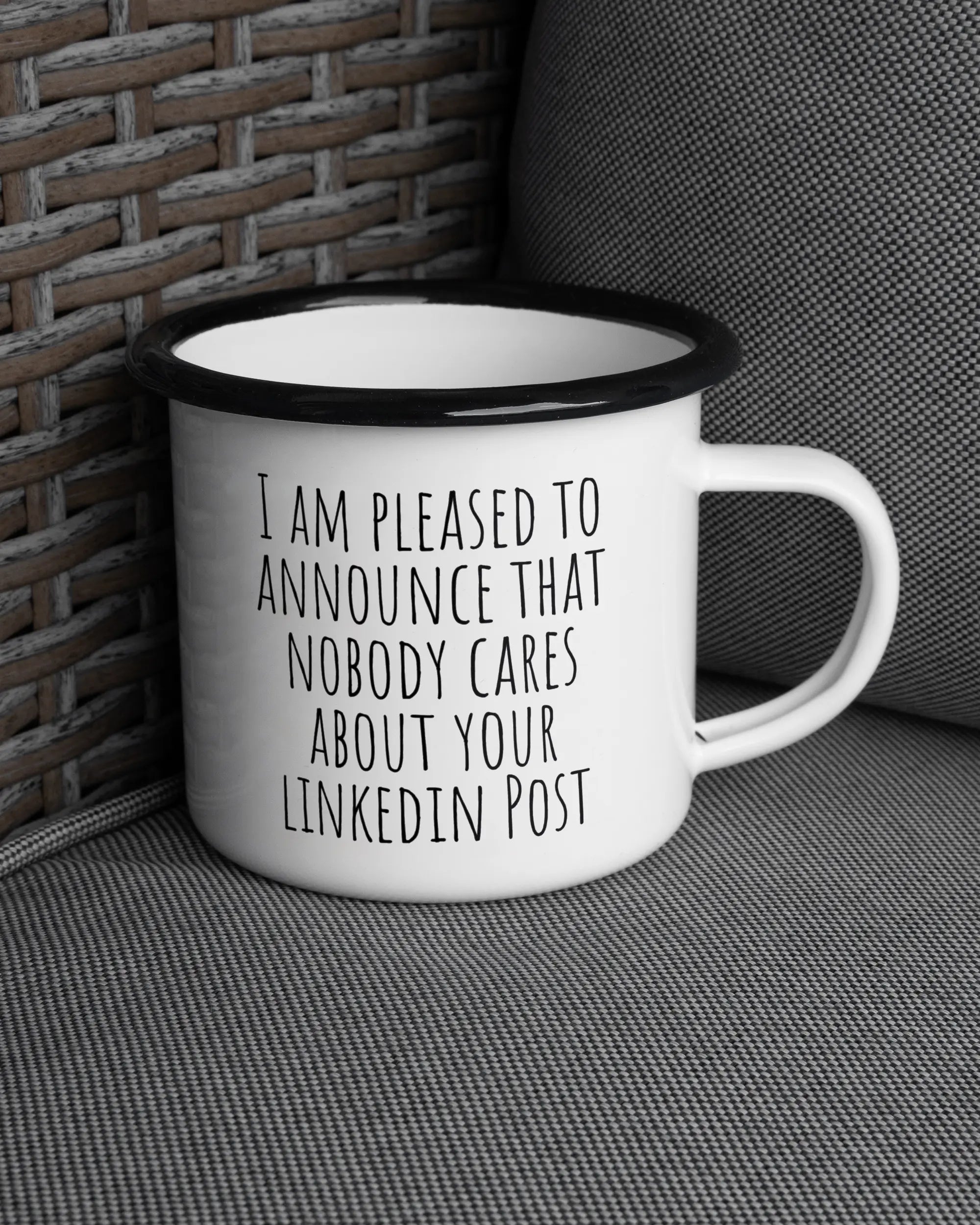 Ansicht der rechten Seite der beidseitig bedruckten Emailletasse von Maondo auf einem Balkonmöbel bzw. Campingstuhl mit dem Design Please Unannounce in der Farbe White-Black