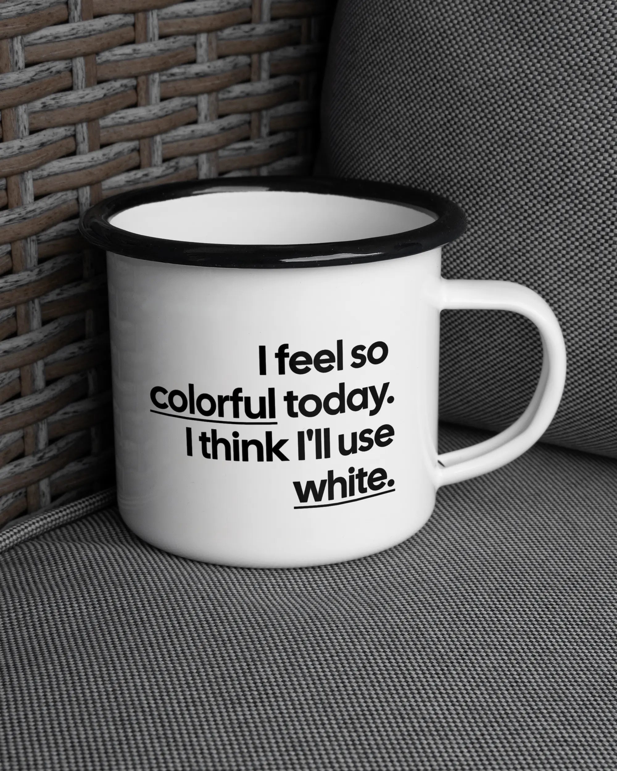 Ansicht der rechten Seite der beidseitig bedruckten Emailletasse von Maondo auf einem Balkonmöbel bzw. Campingstuhl mit dem Design Colorful Day in der Farbe White-Black