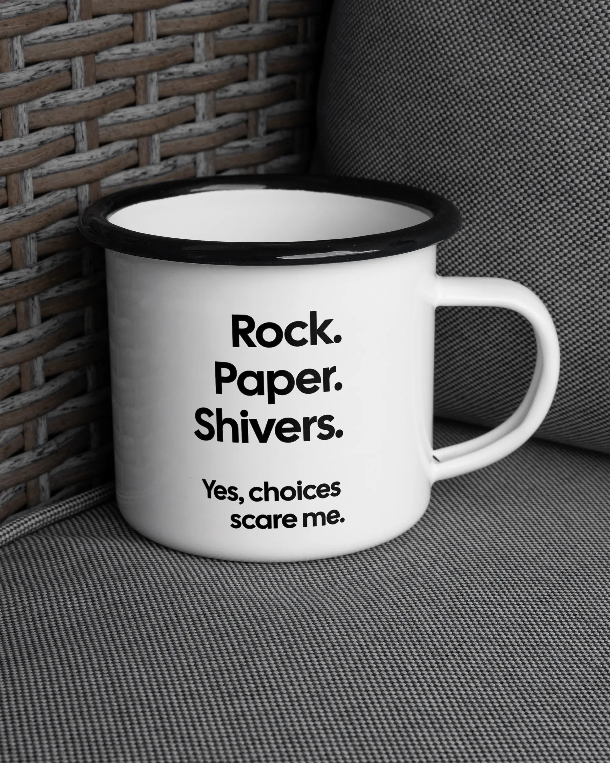 Ansicht der rechten Seite der beidseitig bedruckten Emailletasse von Maondo auf einem Balkonmöbel bzw. Campingstuhl mit dem Design Rock Paper Shivers in der Farbe White-Black