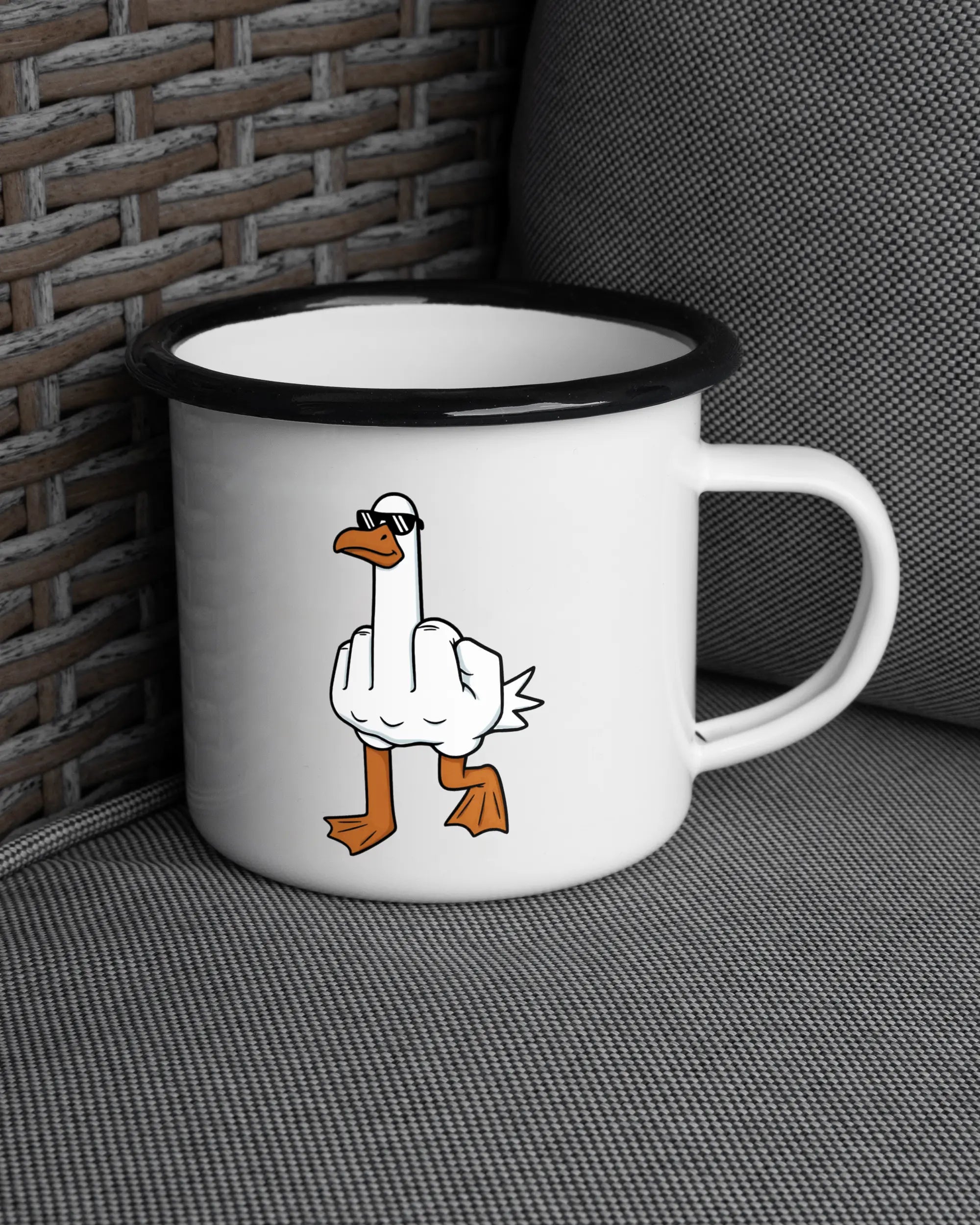 Ansicht der rechten Seite der beidseitig bedruckten Emailletasse von Maondo auf einem Balkonmöbel bzw. Campingstuhl mit dem Design I give a duck in der Farbe White-Black