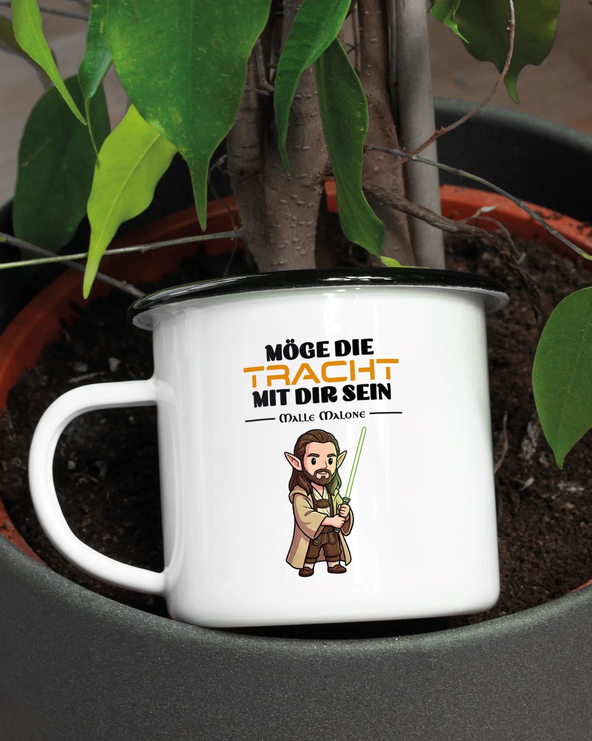 Aufnahme der linken Seite der beidseitig bedruckten Emailletasse von Maondo mit dem Design Tracht mit dir in der Farbe White-Black in einem Blumentopf